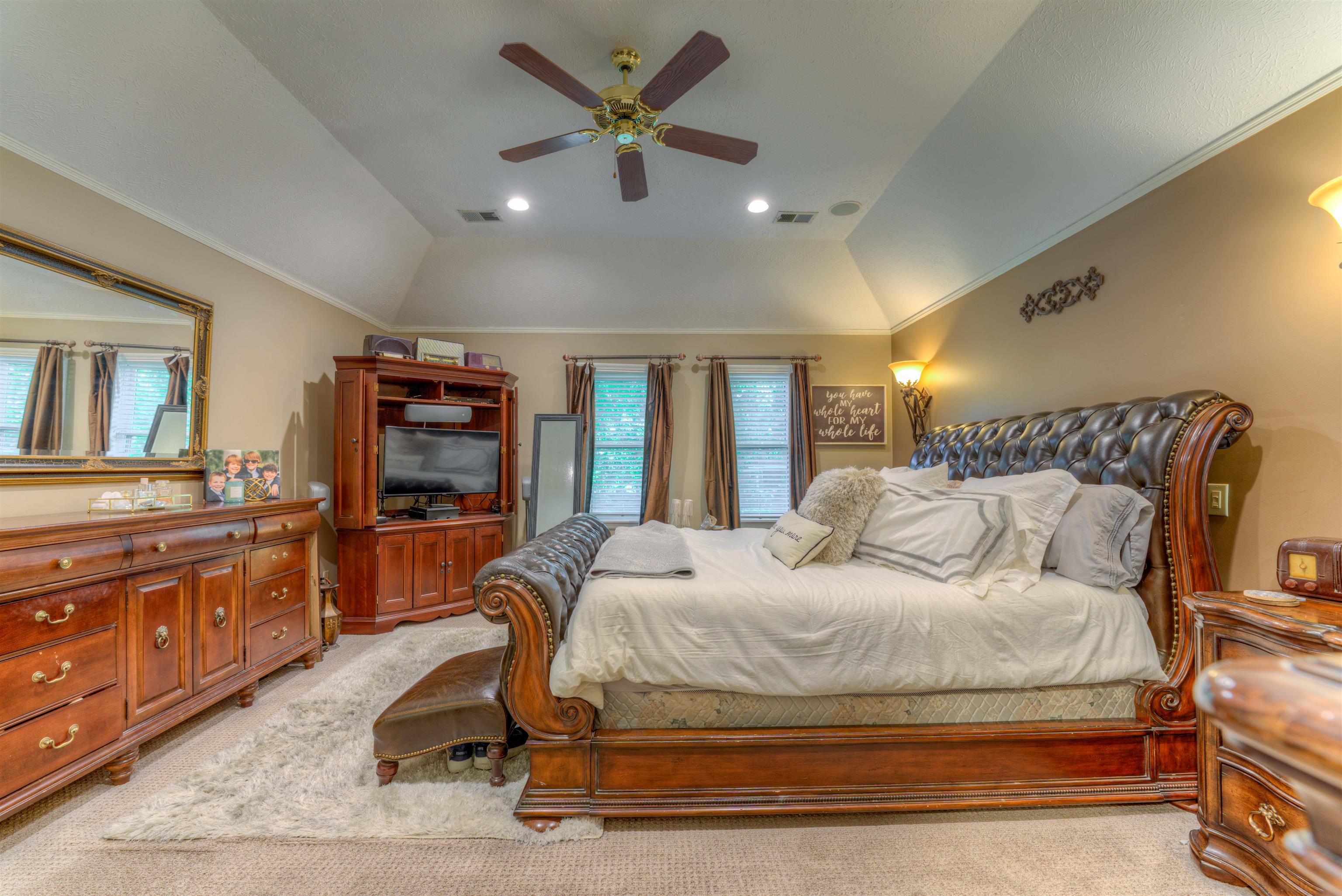 Carpeted bedroom featuring lofted ceiling, ornamental molding, and ceiling fan