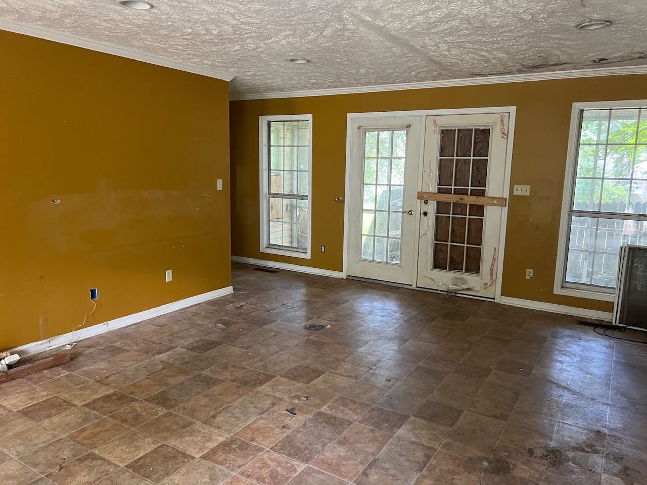 Empty room with a textured ceiling, ornamental molding, and french doors