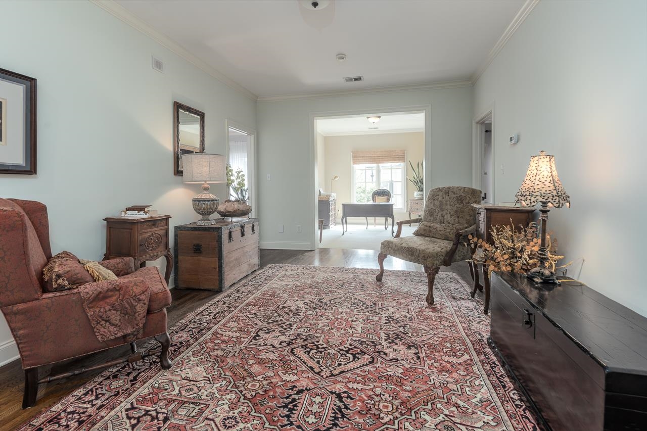 Living area with wood-type flooring and crown molding