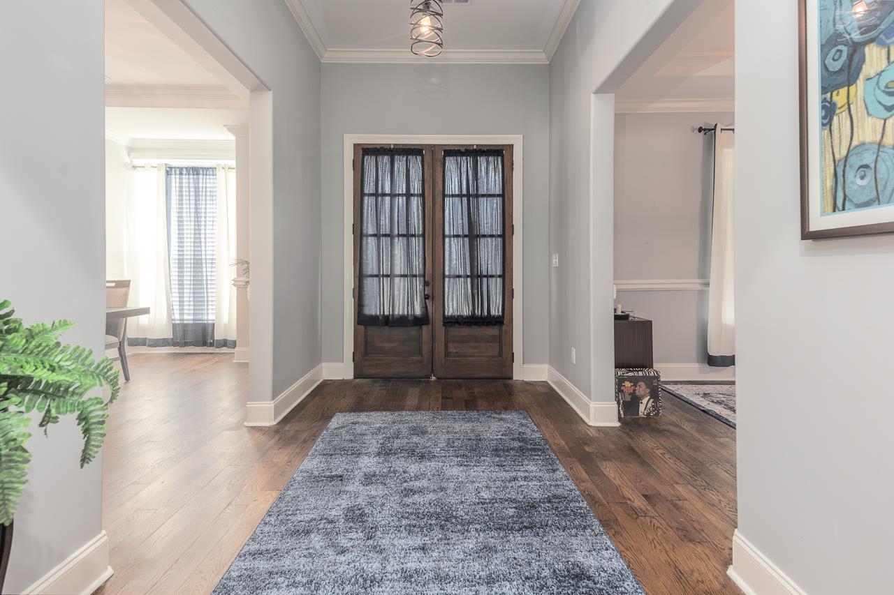 Foyer with crown molding, dark hardwood / wood-style floors, and french doors