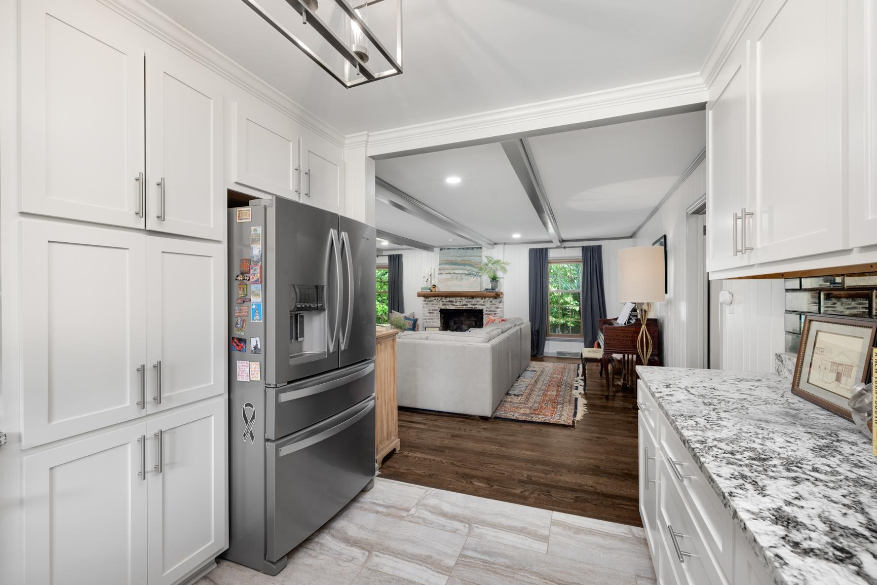 Kitchen featuring light stone counters, white cabinets, crown molding, light hardwood / wood-style flooring, and stainless steel fridge with ice dispenser