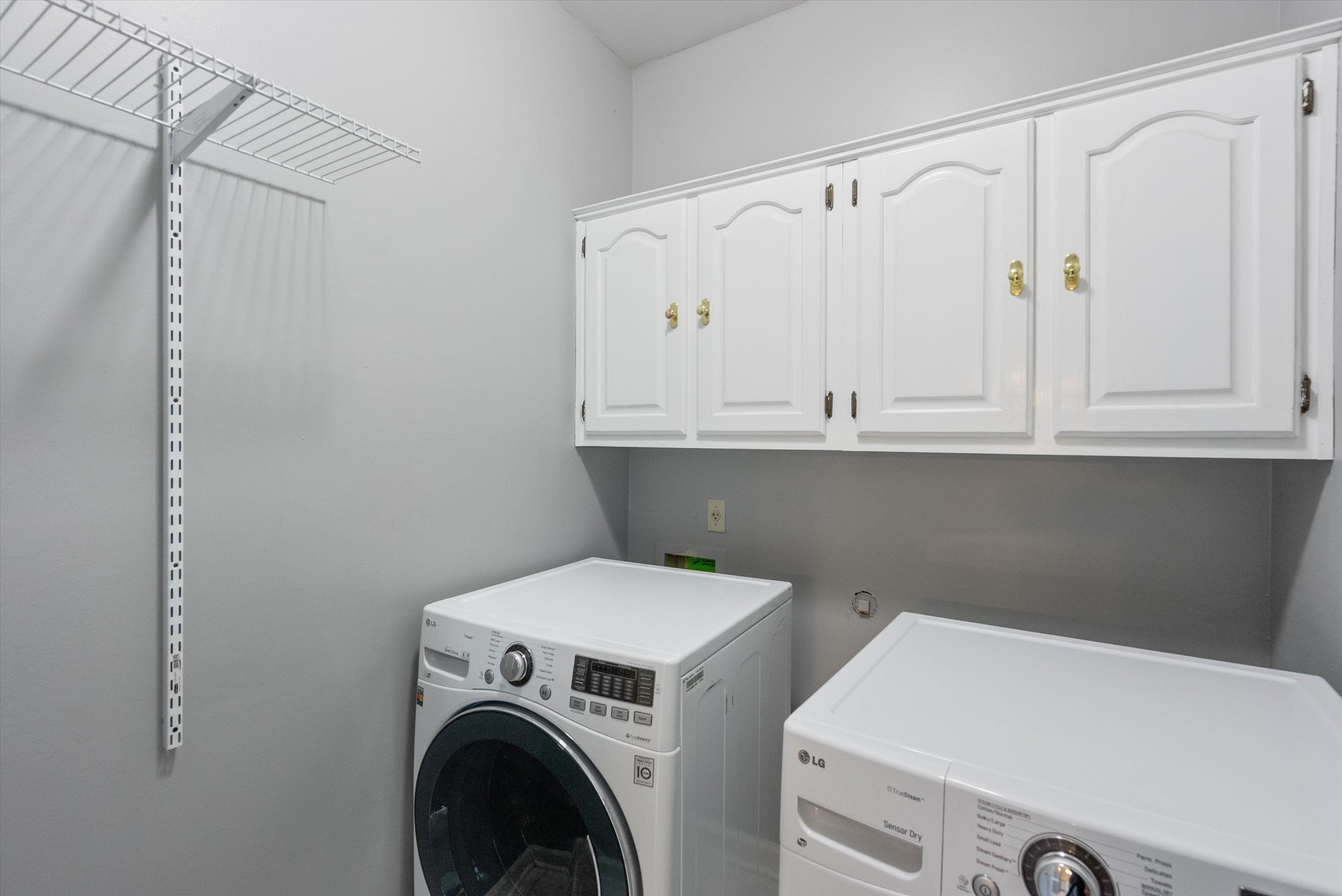 Washroom featuring washing machine and dryer and cabinets