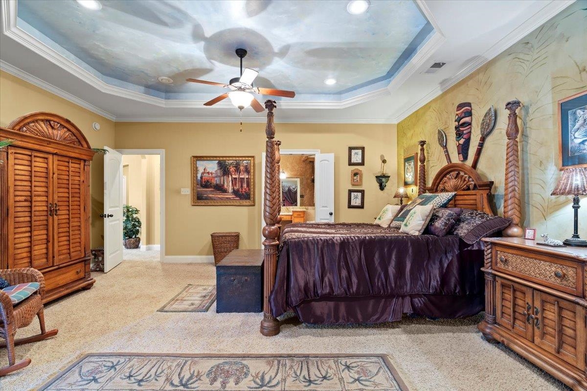 Bedroom featuring ceiling fan, a raised ceiling, light carpet, and crown molding