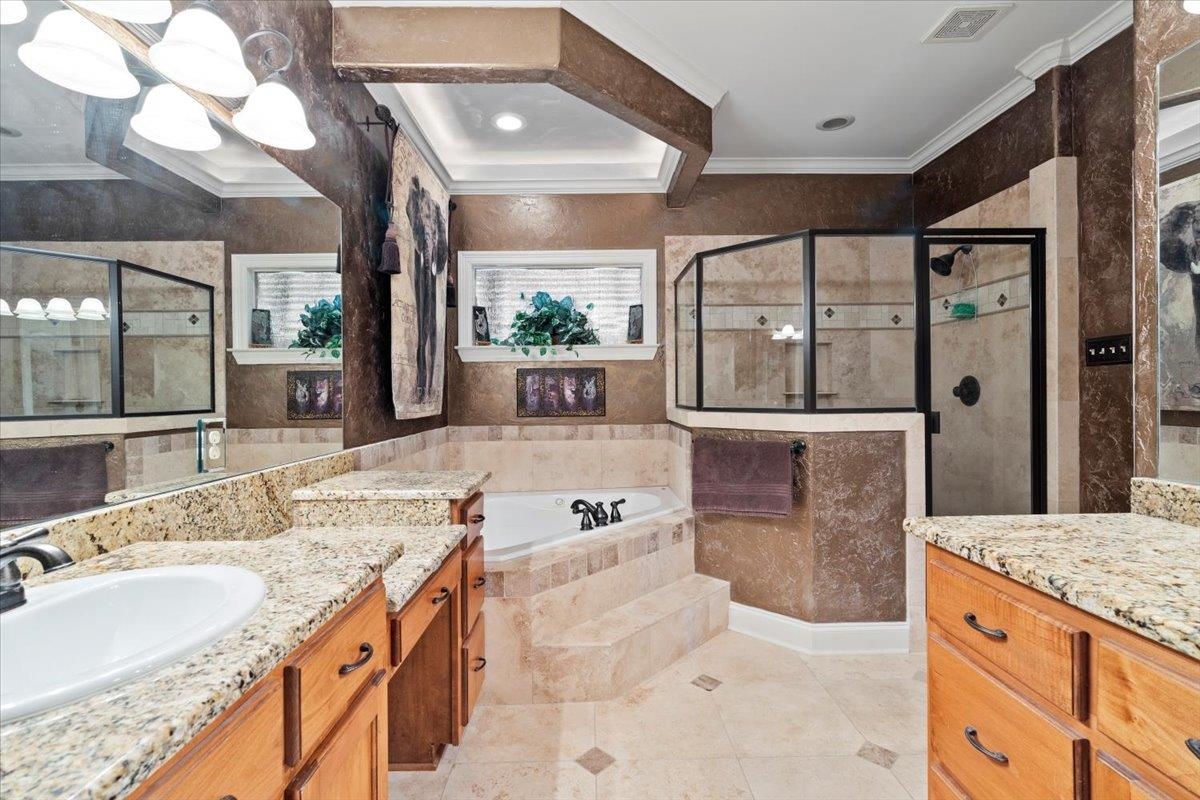 Bathroom with ornamental molding, a wealth of natural light, vanity, and separate shower and tub