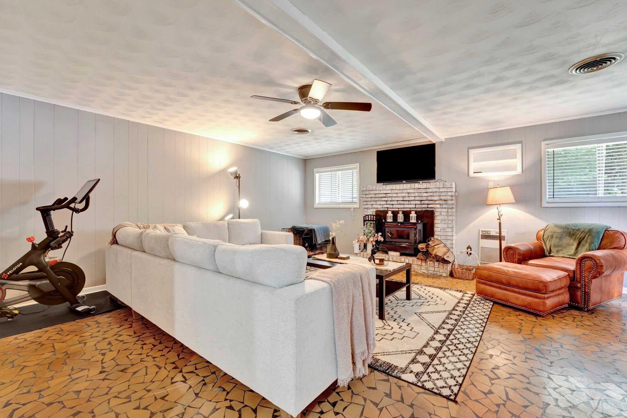 Living room with a brick fireplace, ceiling fan, a healthy amount of sunlight, and a textured ceiling