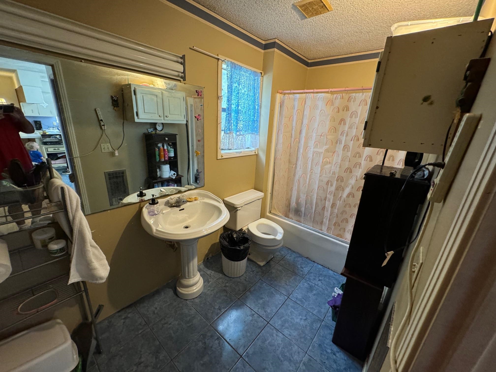 Bathroom with shower / bath combination with curtain, toilet, ornamental molding, a textured ceiling, and tile patterned flooring