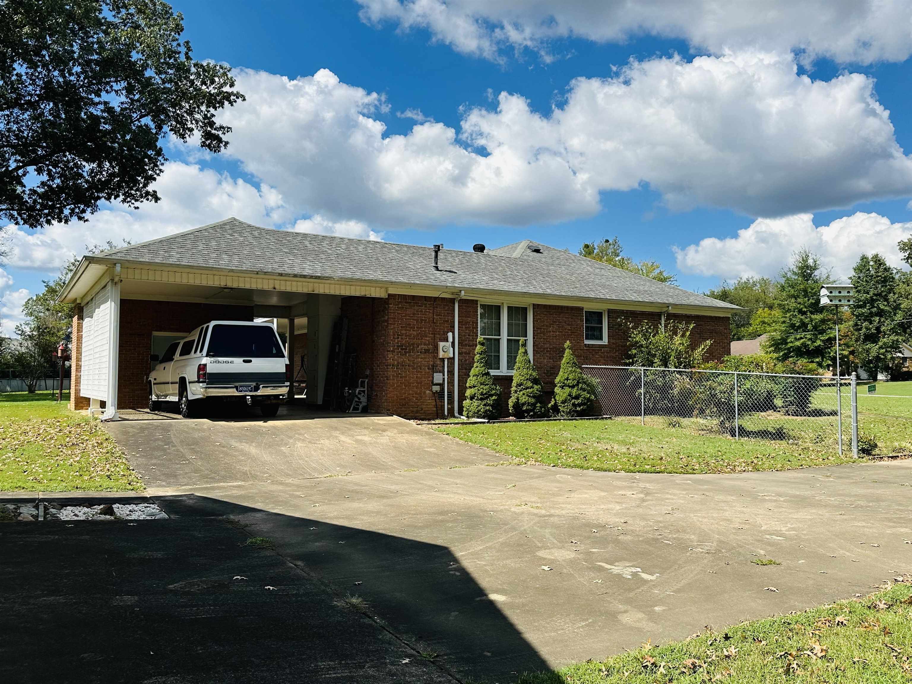 Ranch-style house featuring a front lawn and a carport