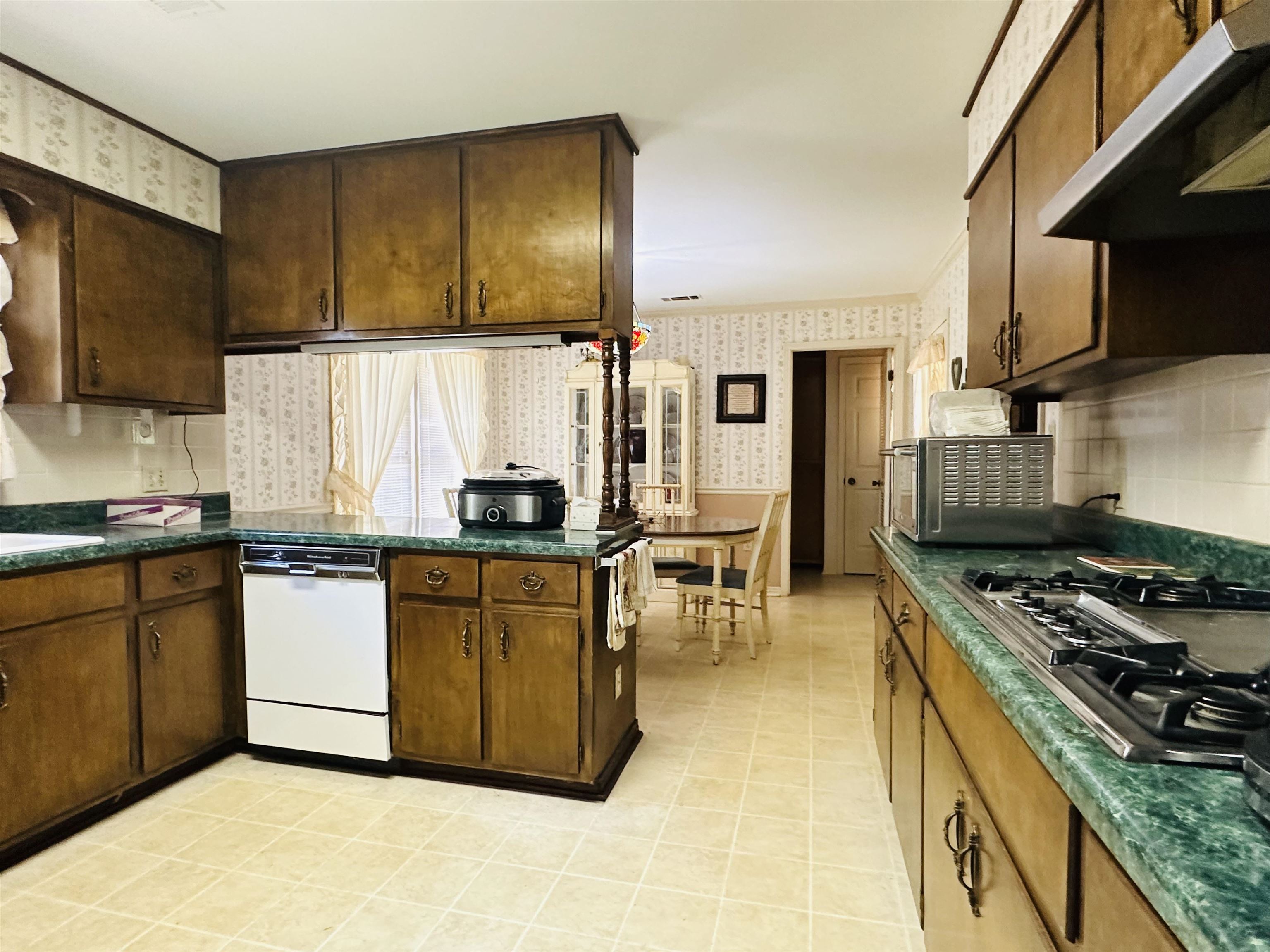 Kitchen with dark brown cabinets, stainless steel appliances, and light tile patterned floors