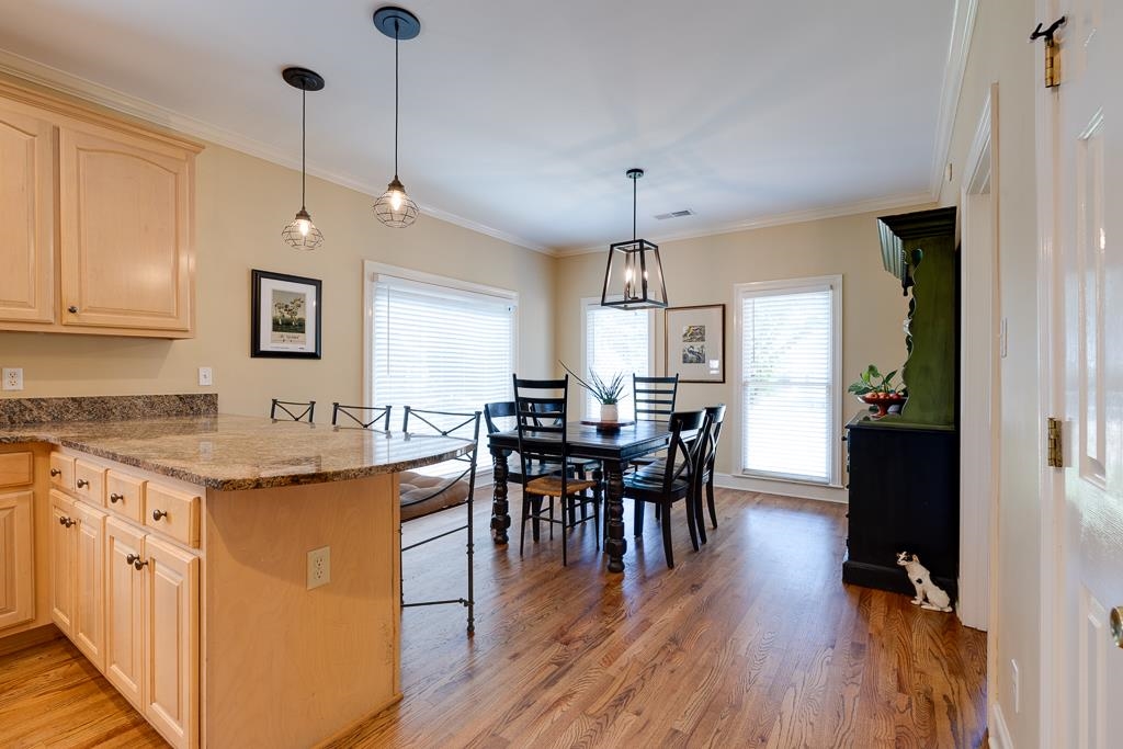 Kitchen with crown molding, kitchen peninsula, pendant lighting, and hardwood / wood-style flooring