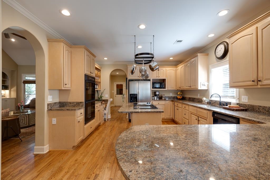 Kitchen featuring ornamental molding, sink, a kitchen island, light hardwood / wood-style flooring, and black appliances