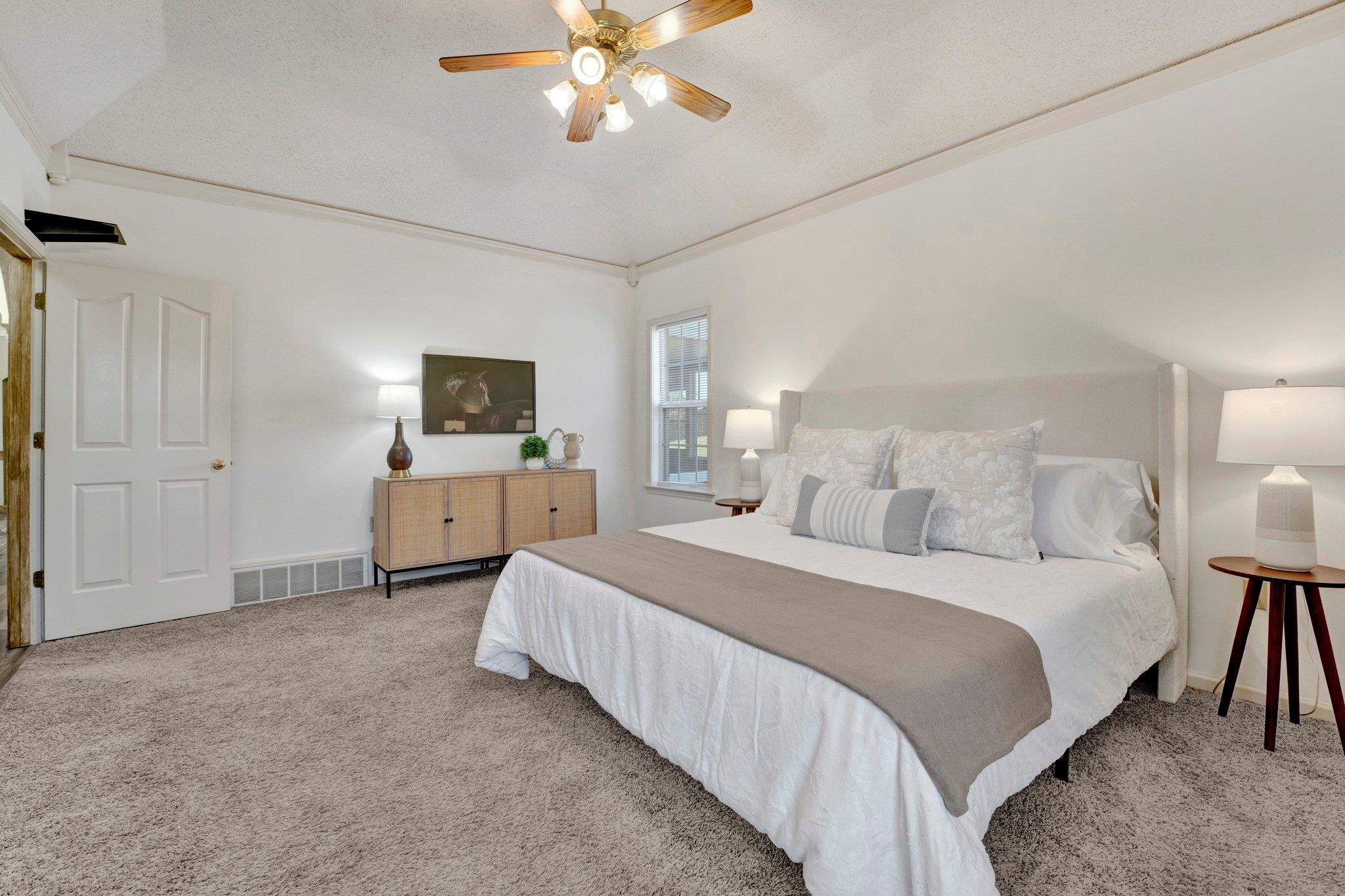 Carpeted bedroom featuring vaulted ceiling and ceiling fan