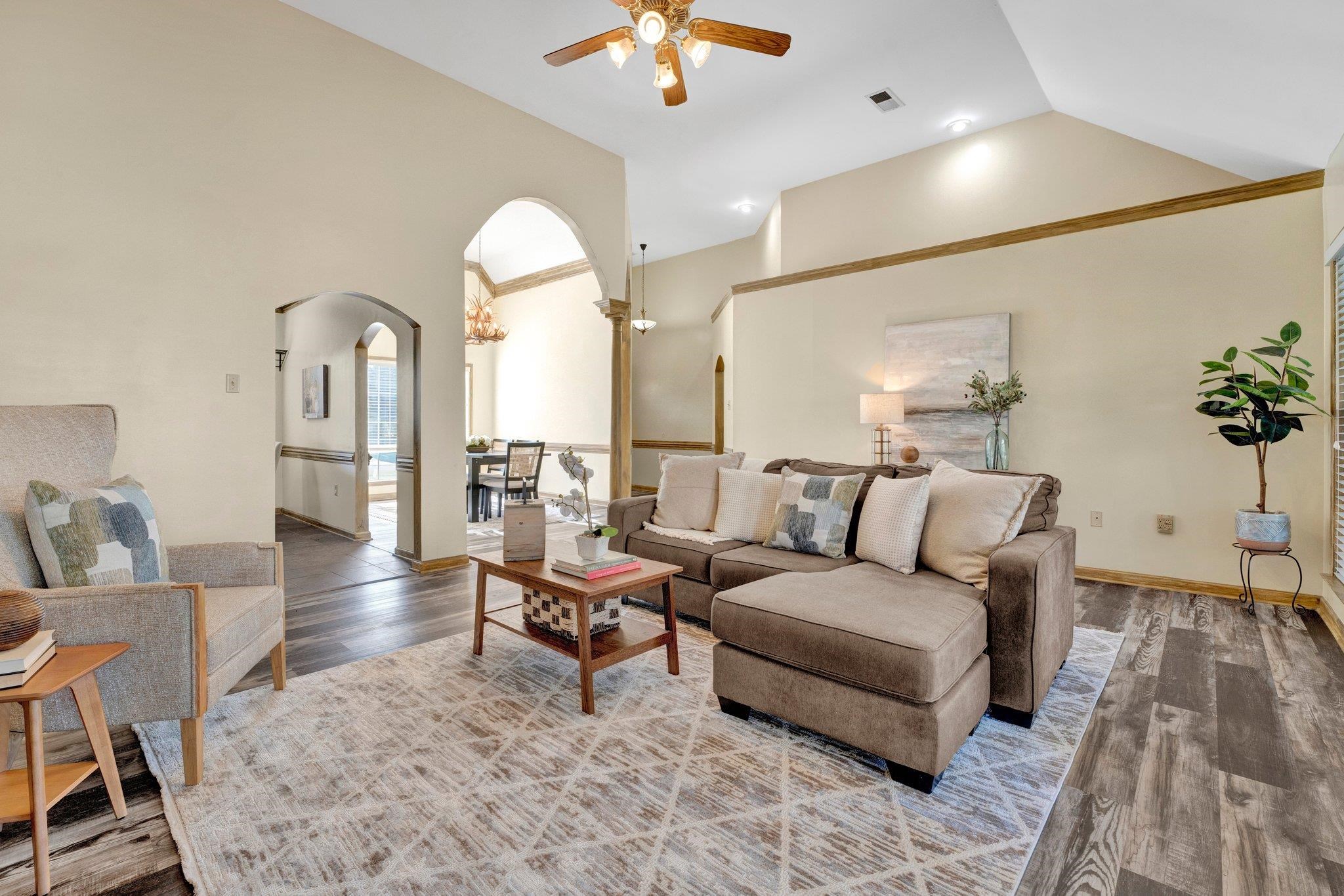 Living room featuring crown molding, vaulted ceiling, ceiling fan, and hardwood / wood-style flooring