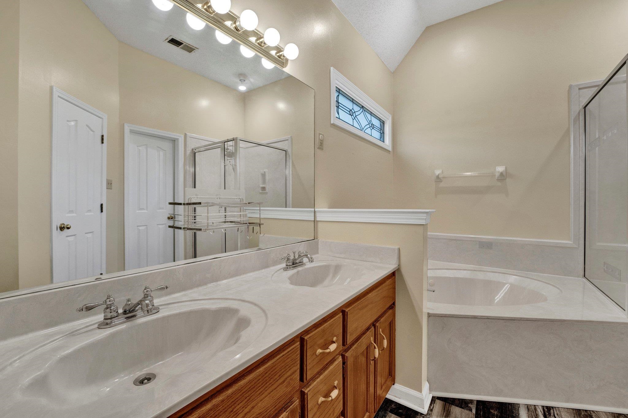 Bathroom with vaulted ceiling, hardwood / wood-style flooring, vanity, and separate shower and tub