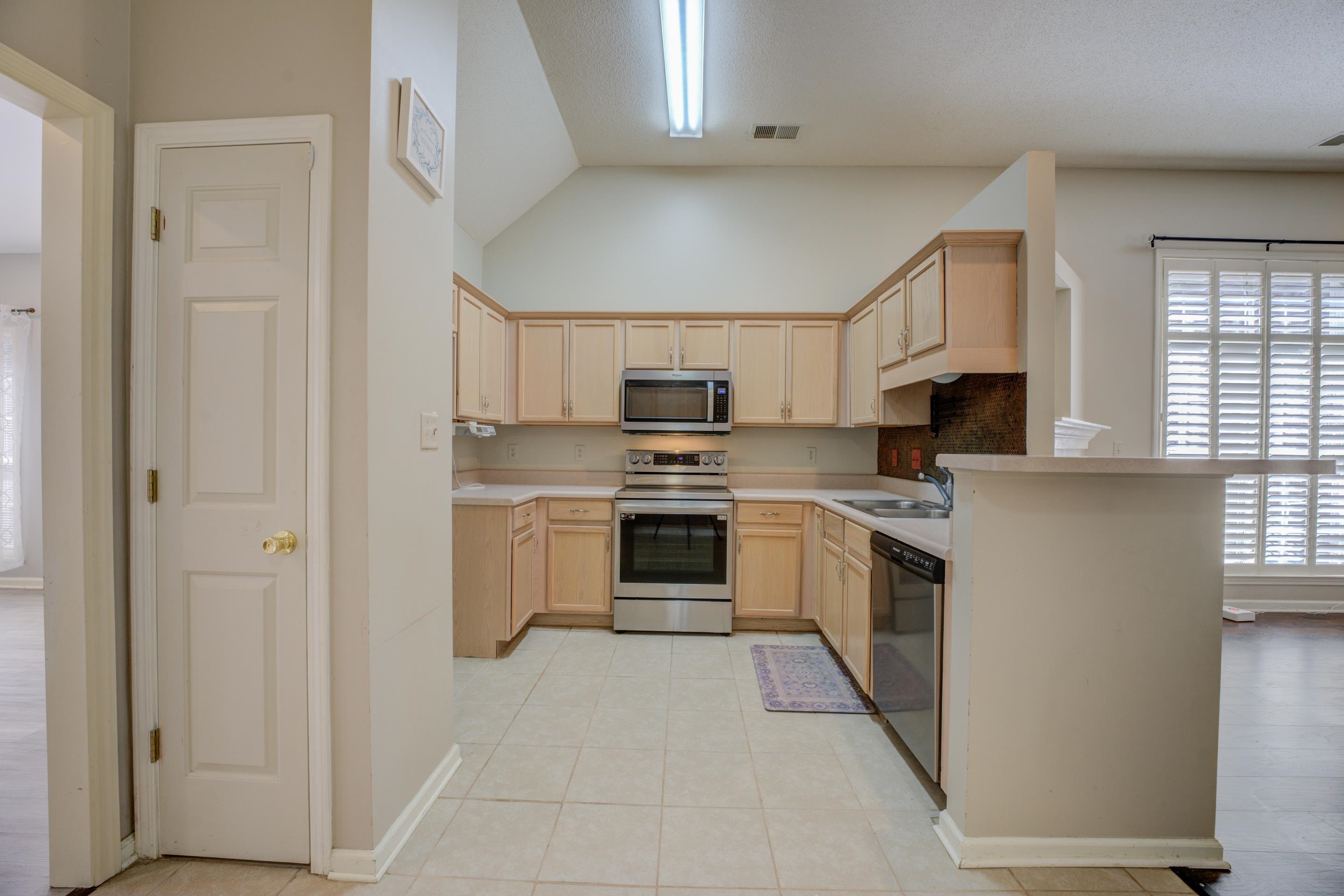 Kitchen featuring stainless steel appliances, light brown cabinets, and a healthy amount of sunlight