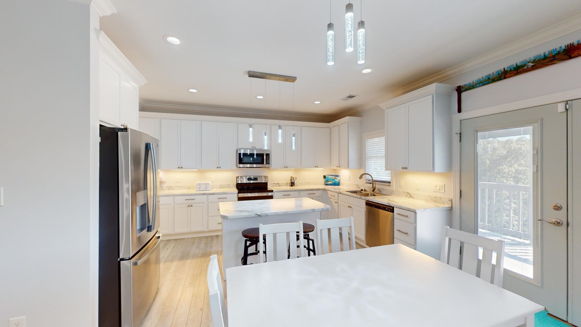 Kitchen with stainless steel appliances, white cabinets, hanging light fixtures, and a kitchen island