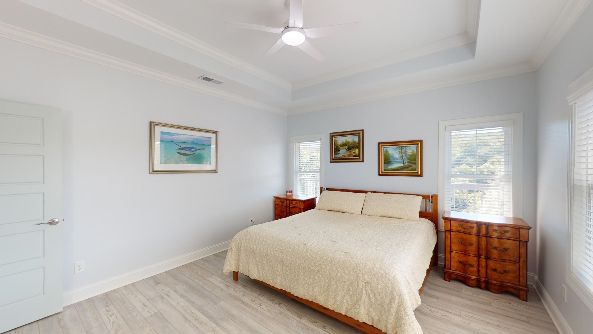 Bedroom with crown molding, a tray ceiling, ceiling fan, and light hardwood / wood-style flooring