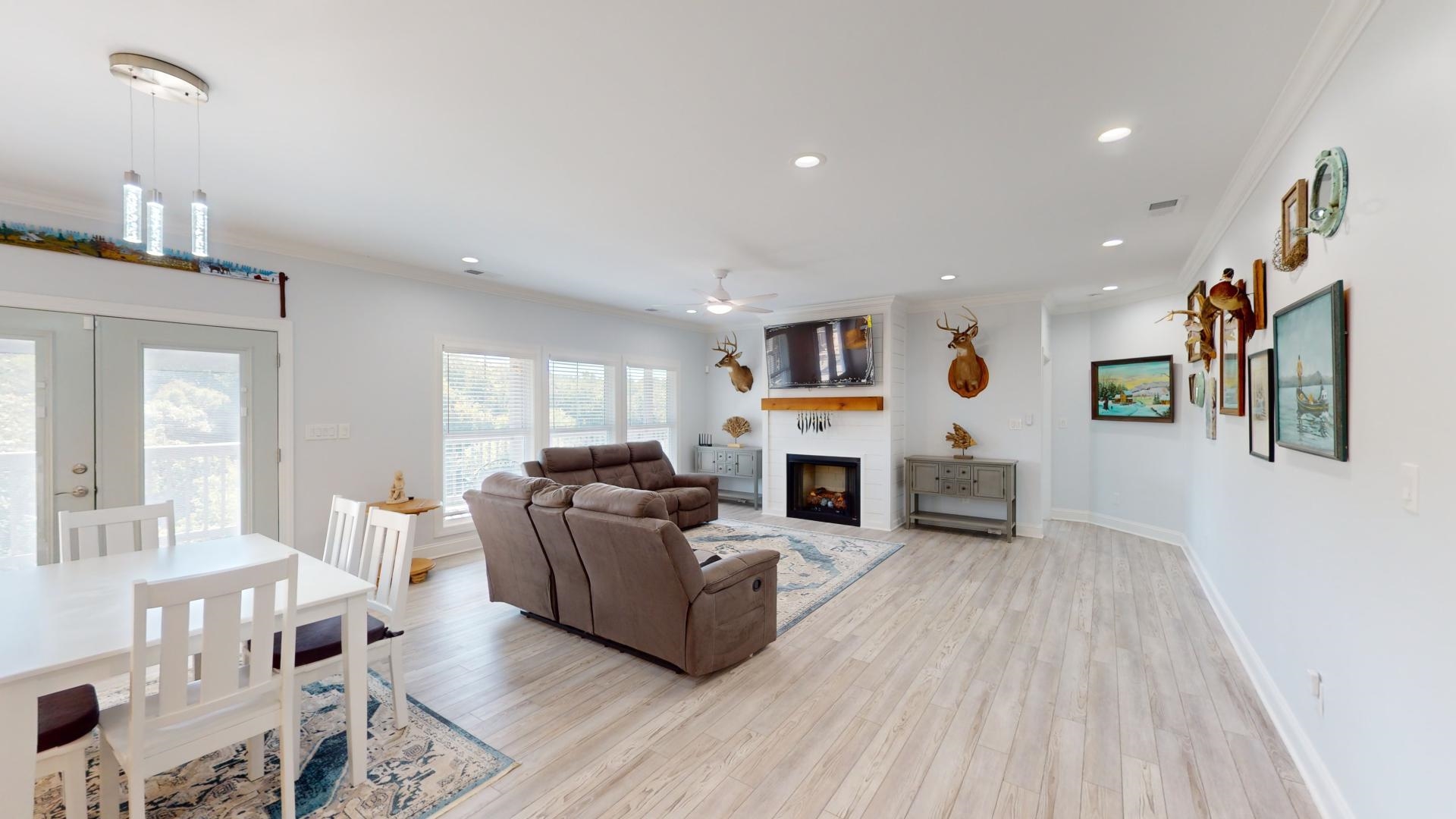 Living room featuring ceiling fan, a fireplace, ornamental molding, and light hardwood / wood-style flooring