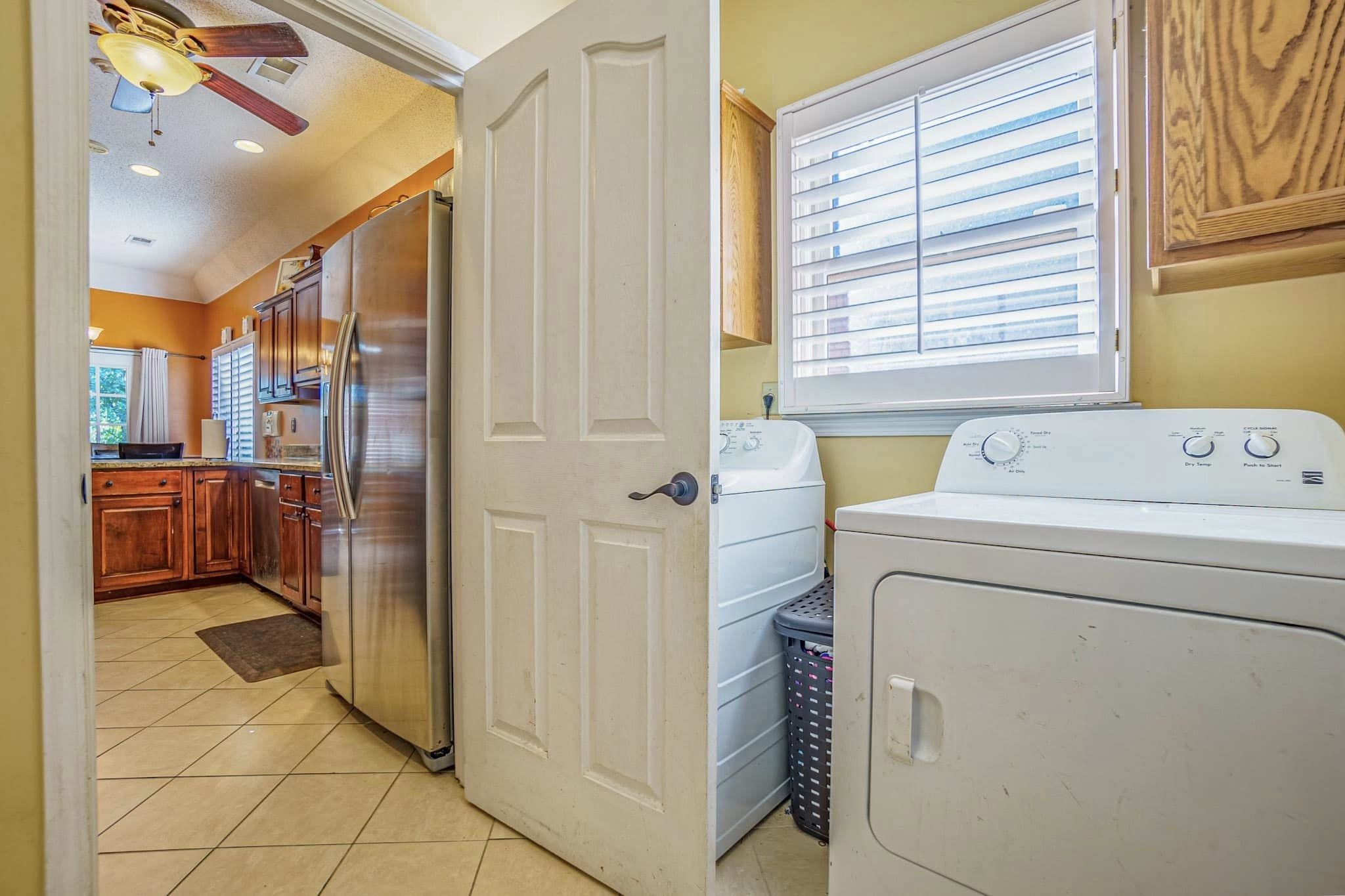 Clothes washing area featuring a textured ceiling, washing machine and dryer, light tile patterned flooring, and ceiling fan