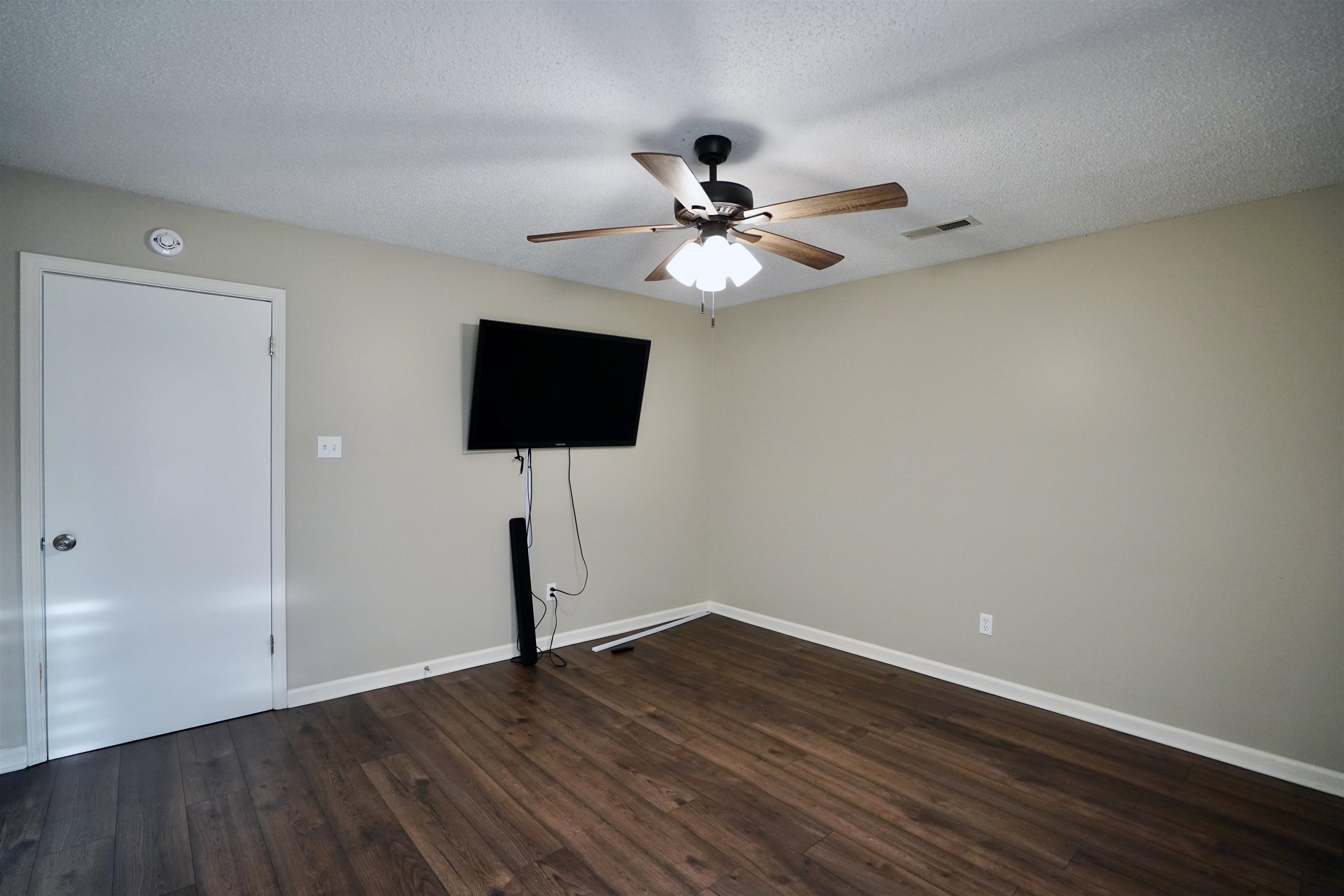 Spare room featuring a textured ceiling, ceiling fan, and dark hardwood / wood-style flooring