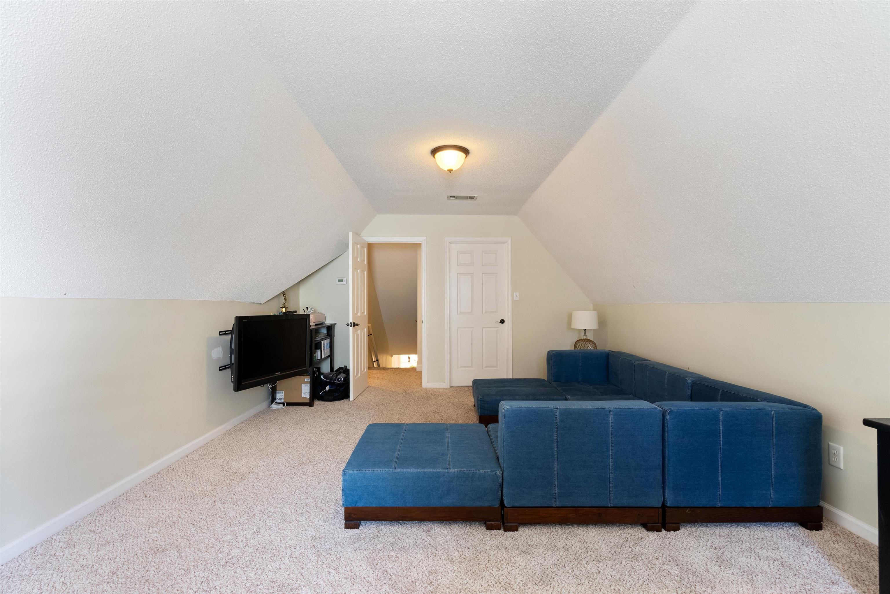 Interior space featuring lofted ceiling, carpet, and a textured ceiling