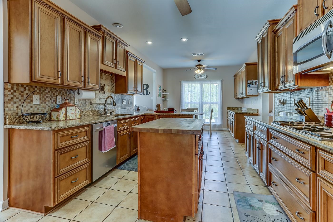 Kitchen with a center island, light tile patterned flooring, sink, stainless steel appliances, and ceiling fan