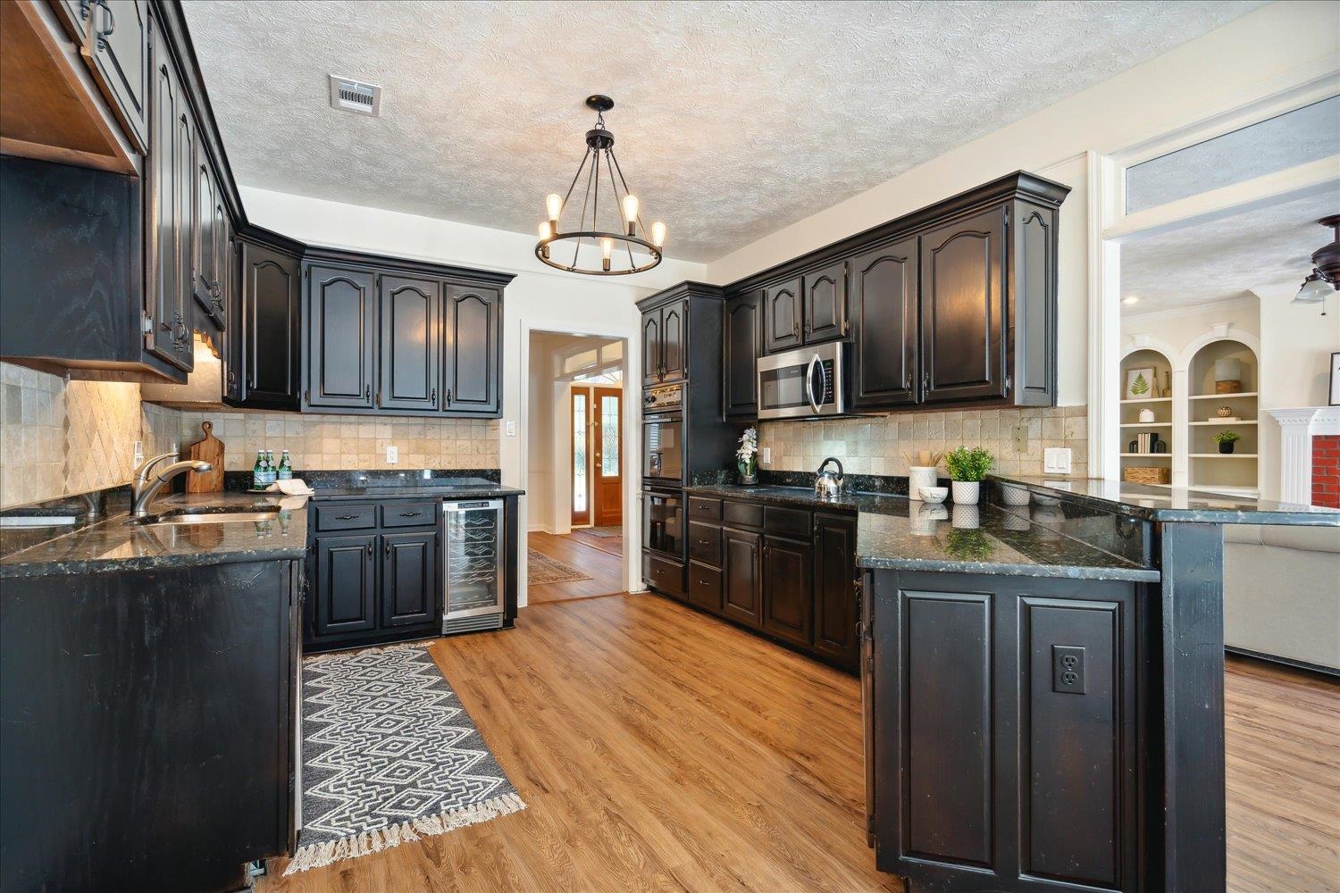 Kitchen with a textured ceiling, light hardwood / wood-style floors, sink, and pendant lighting