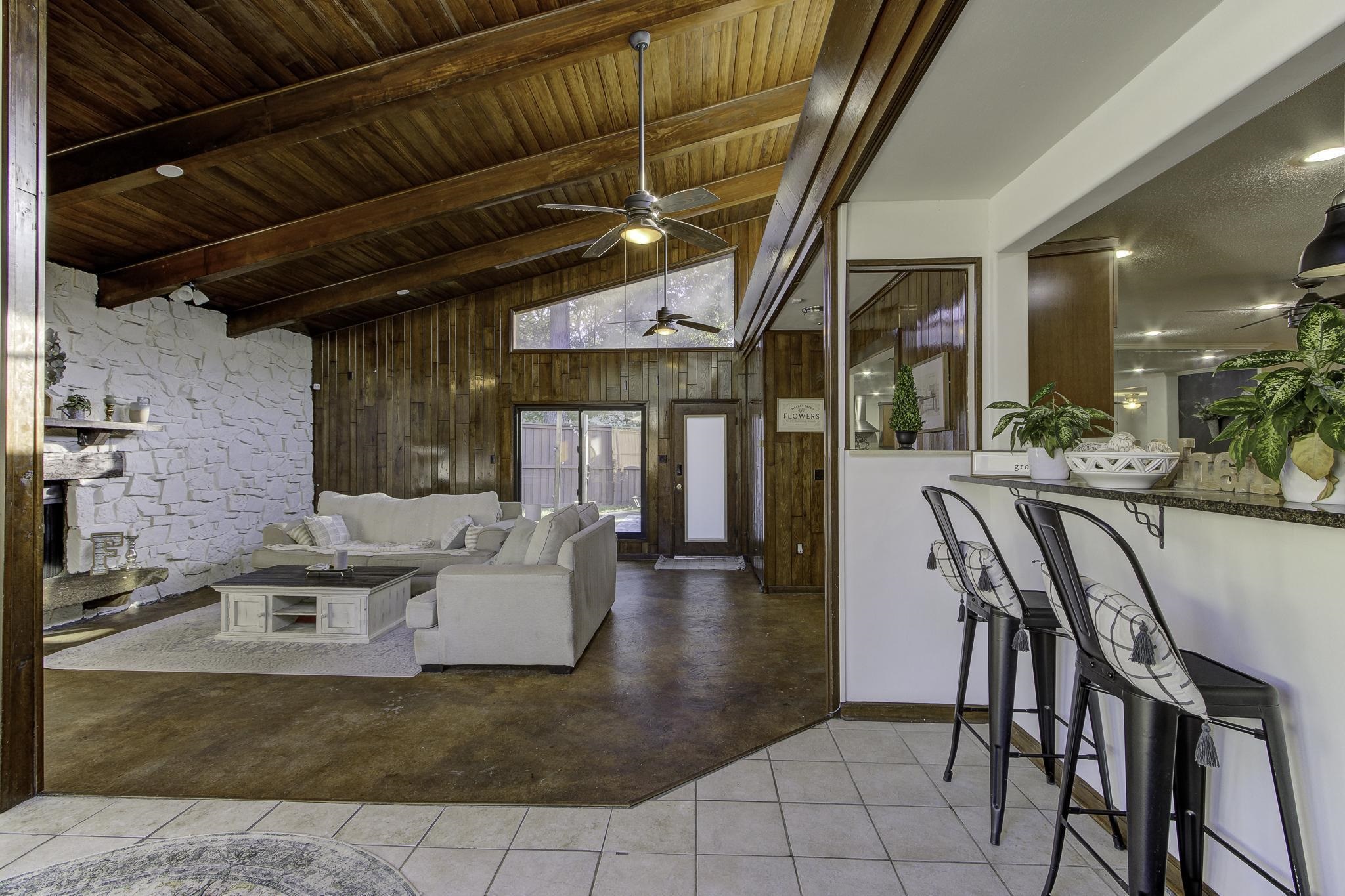 Entering the incredible den gives the feel of being in the mountains - the room is surrounded by natural wood, a stone wood-burning fireplace, incredible natural light, and entry into two separate patios/sections of the back yard.