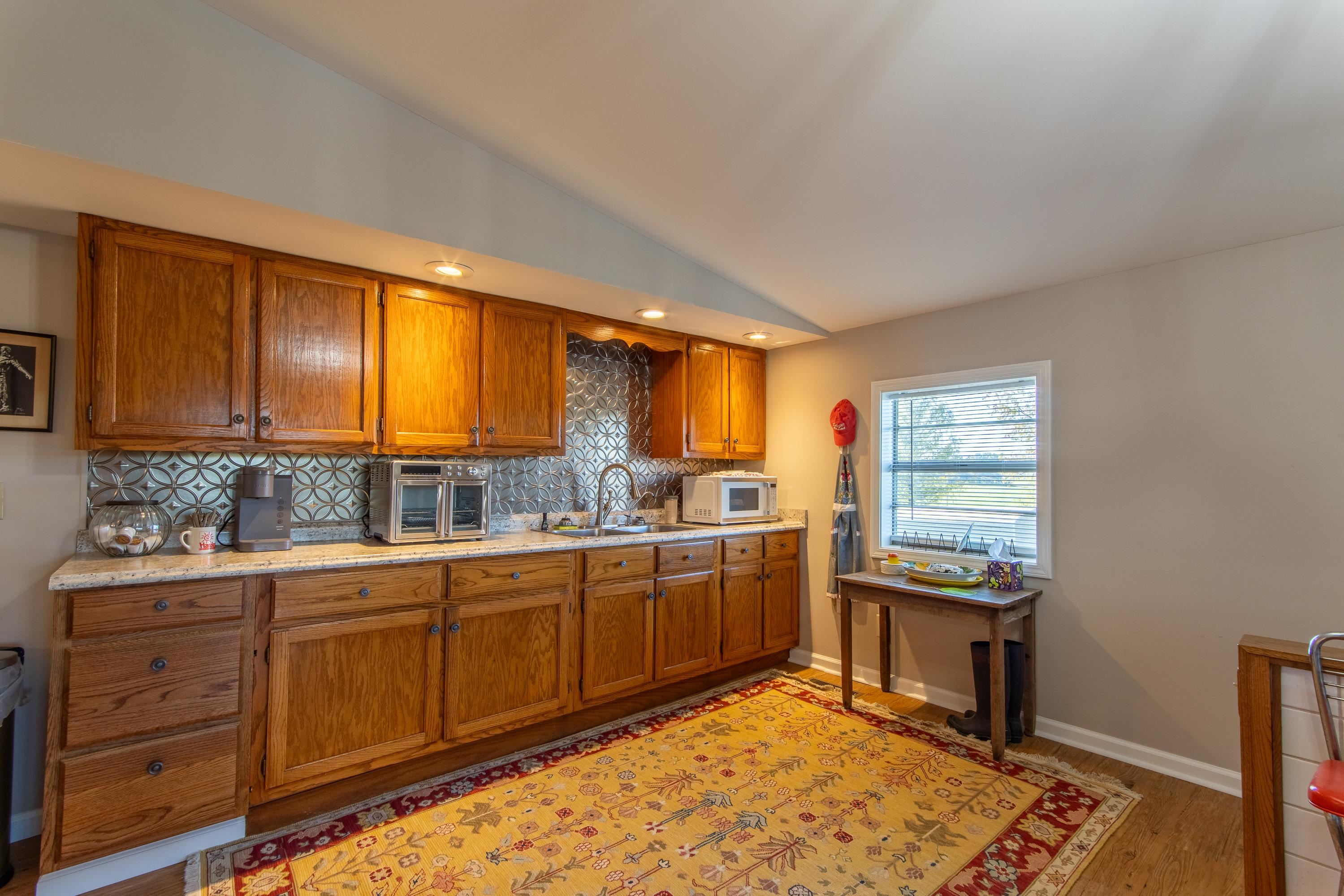 Kitchen featuring backsplash, vaulted ceiling, light hardwood / wood-style floors, and sink