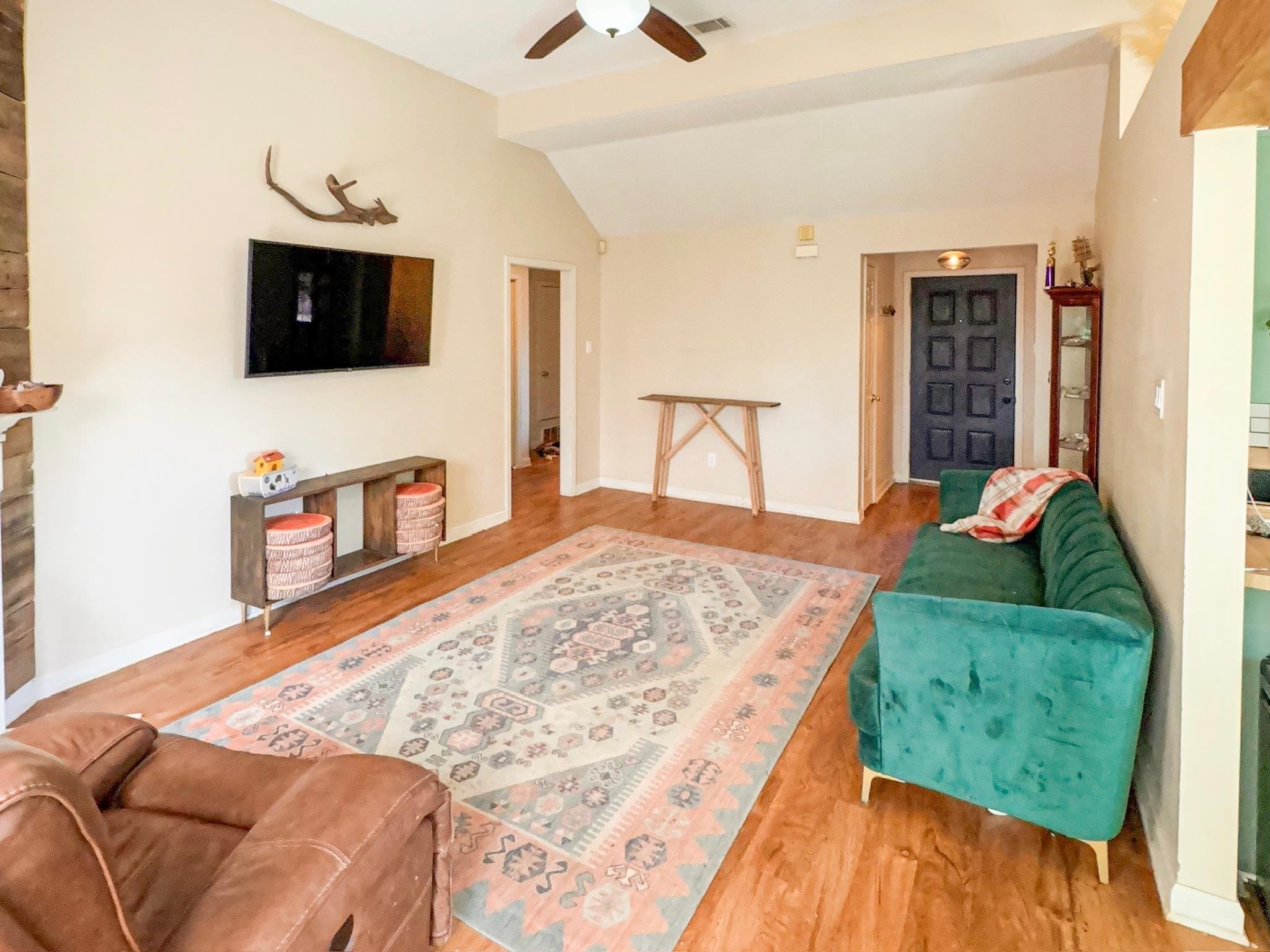 Living room featuring vaulted ceiling, ceiling fan, luxury vinyl flooring