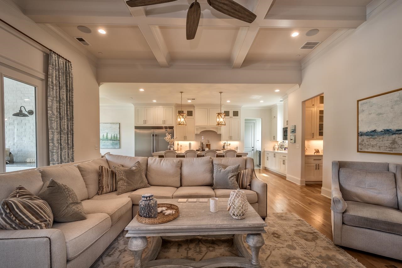 Living room featuring ceiling fan, beam ceiling, light hardwood / wood-style flooring, coffered ceiling, and crown molding