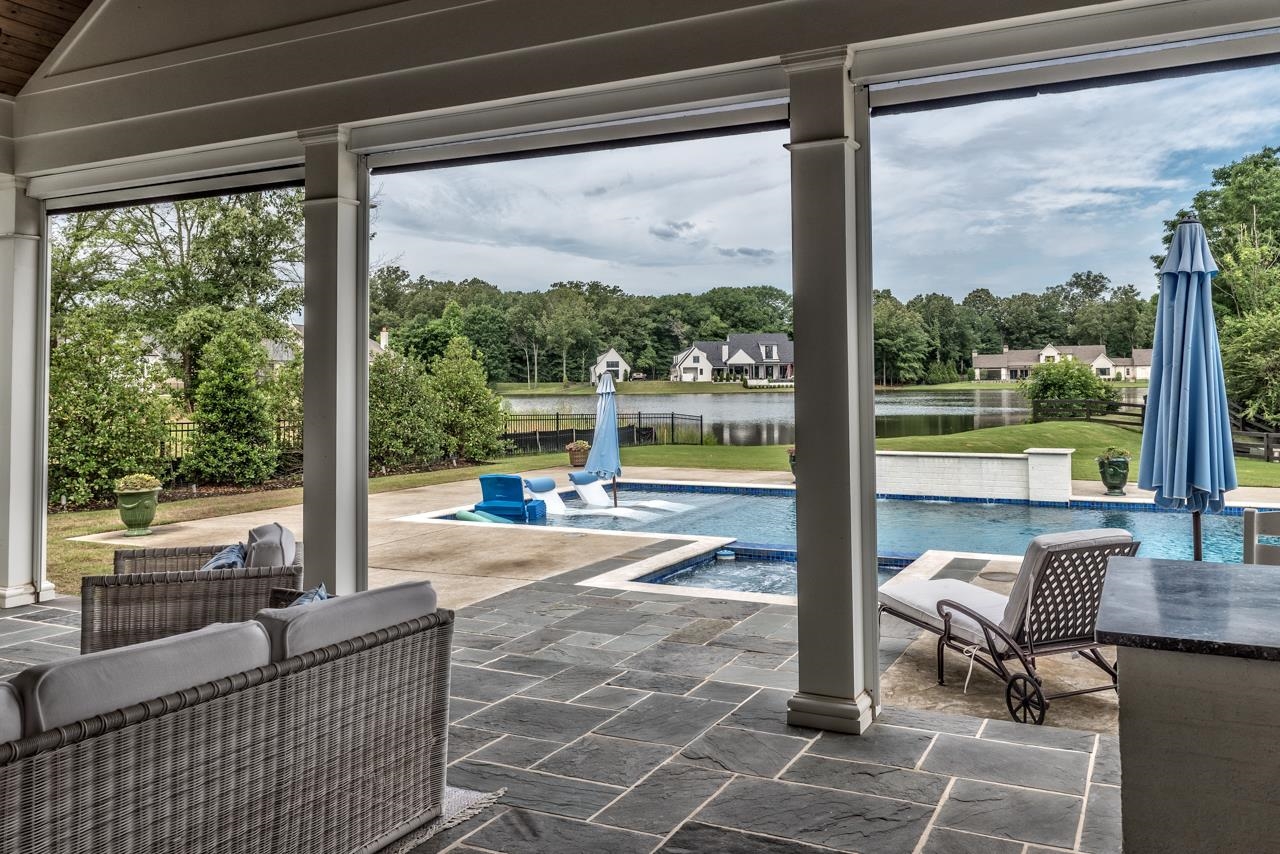 View of pool with a patio, a jacuzzi, a water view, and pool water feature