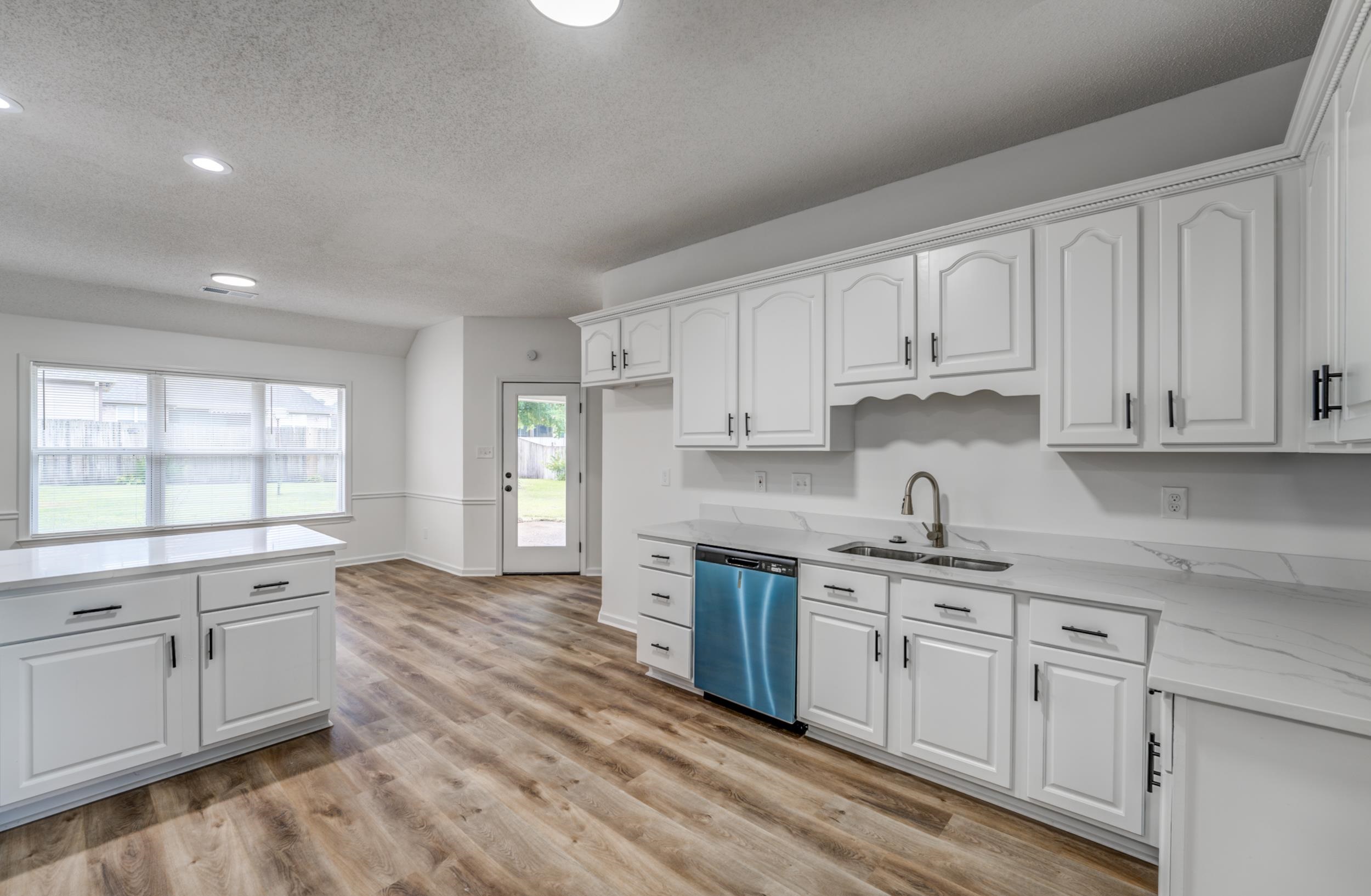 Kitchen featuring light hardwood / wood-style floors, sink, stainless steel dishwasher, and white cabinets