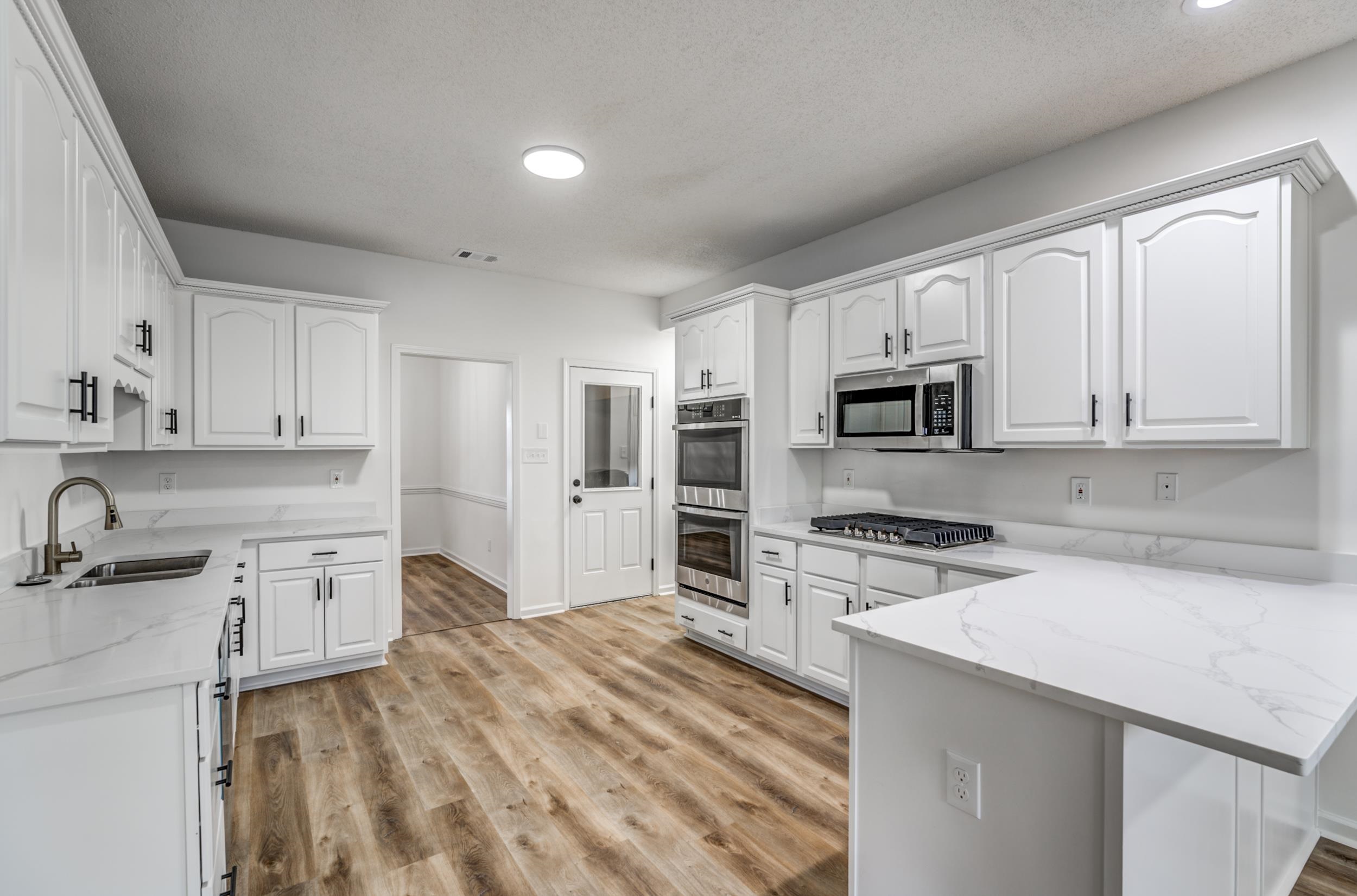 Kitchen with sink, light hardwood / wood-style flooring, white cabinetry, and stainless steel appliances