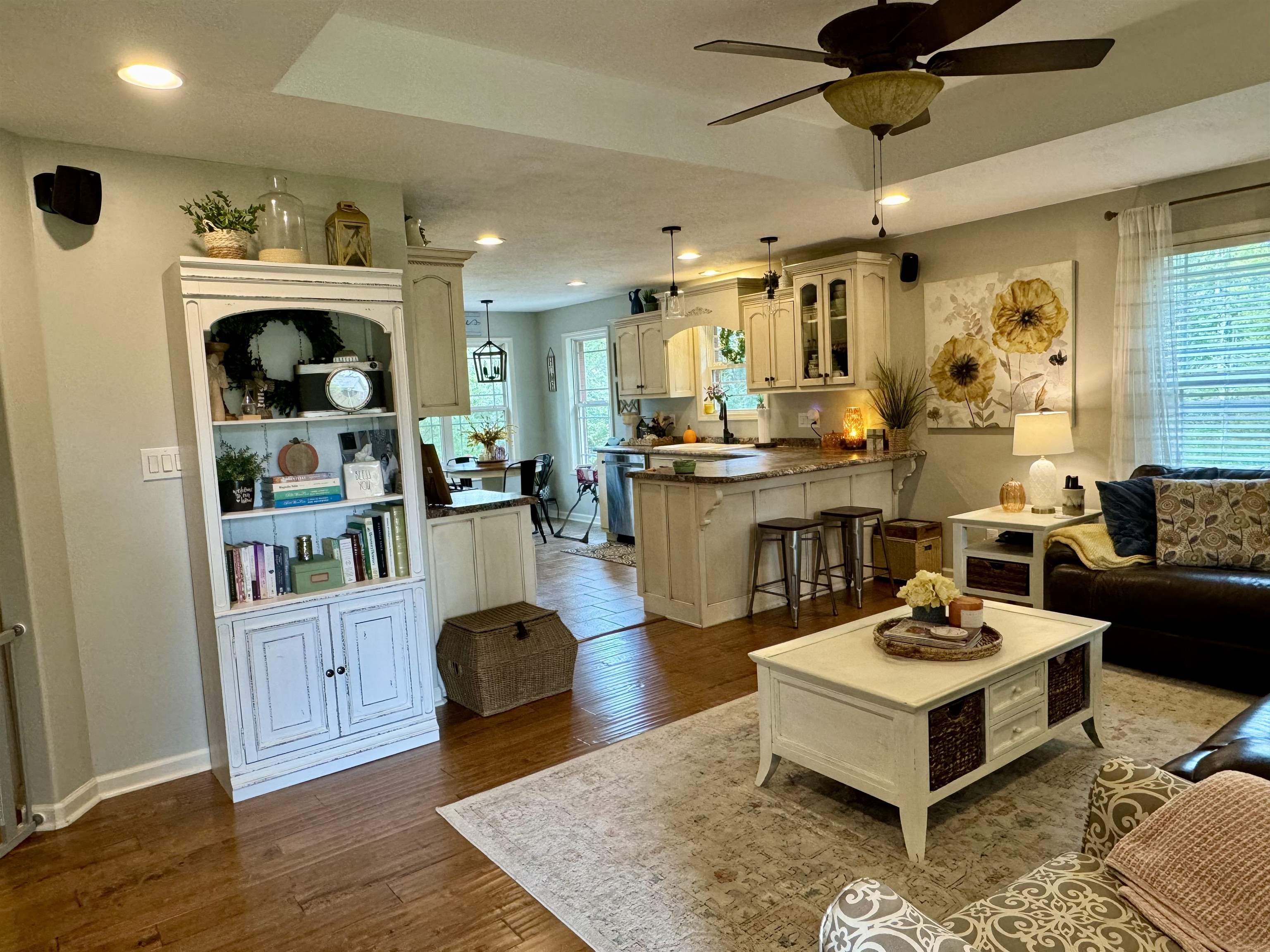 Living room featuring ceiling fan, hardwood / wood-style flooring, and a tray ceiling