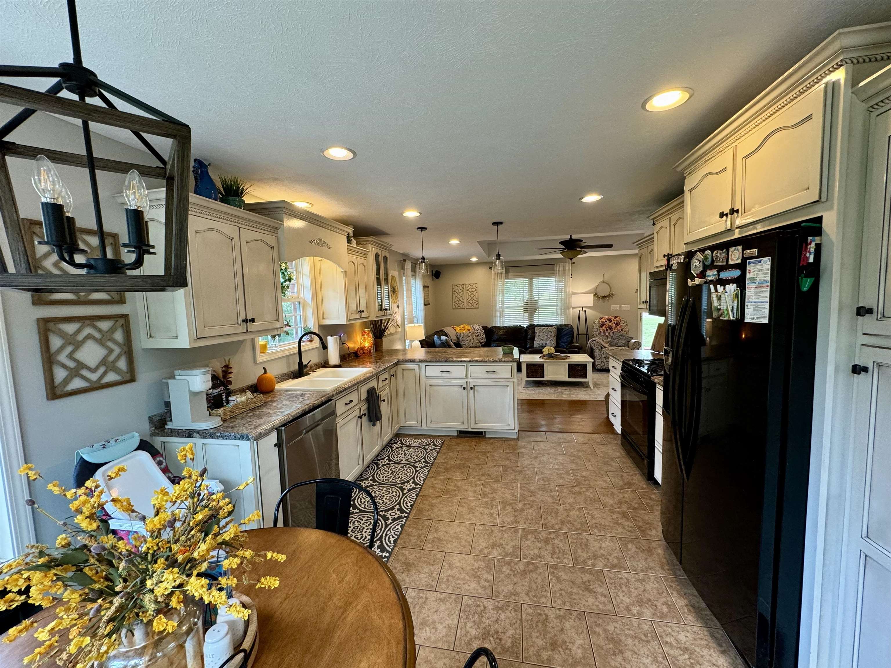 Kitchen featuring black appliances, ceiling fan, decorative light fixtures, and sink
