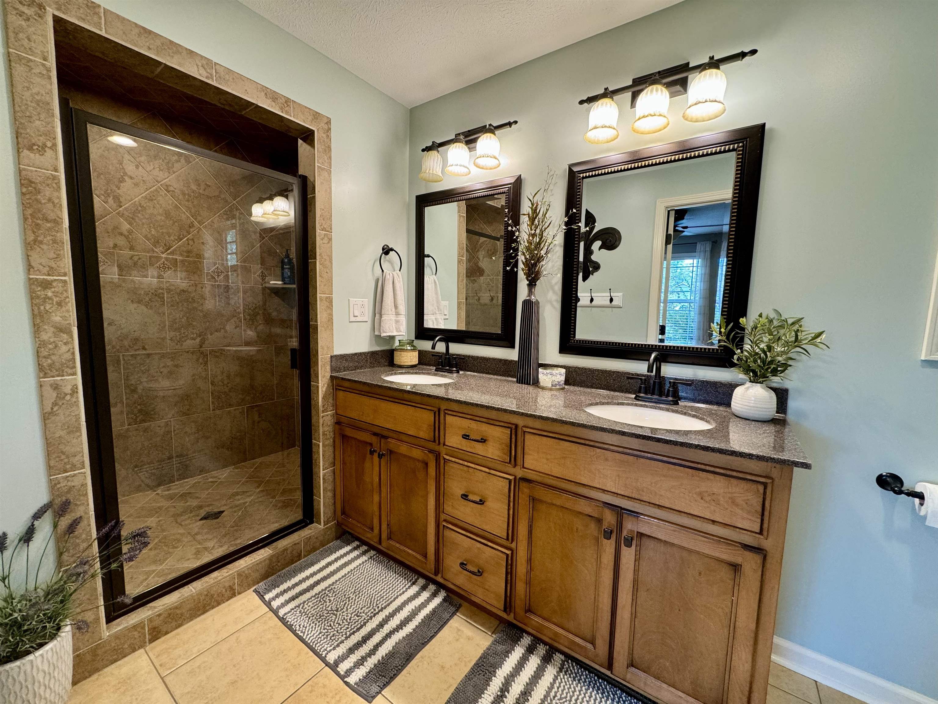 Bathroom with tile patterned floors, a textured ceiling, walk in shower, and vanity
