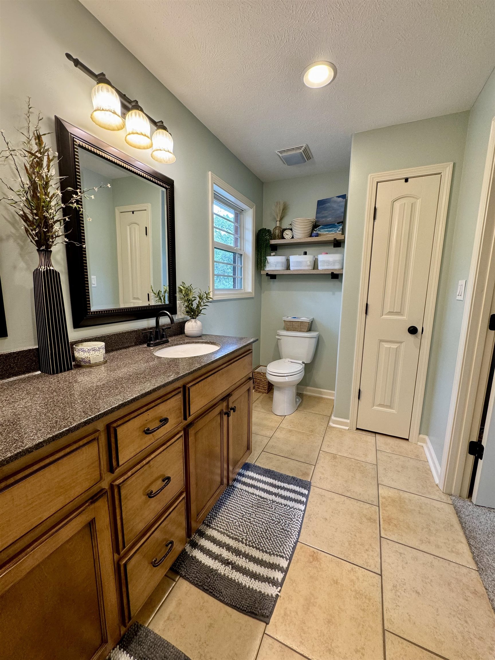 Bathroom with vanity, tile patterned flooring, toilet, and a textured ceiling