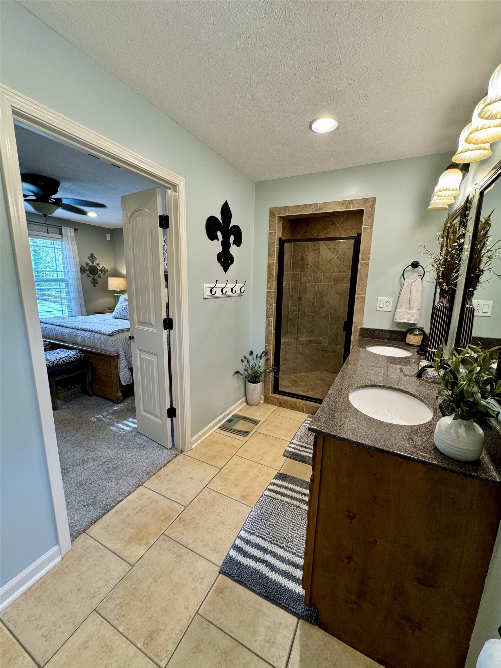 Bathroom featuring a textured ceiling, walk in shower, tile patterned floors, ceiling fan, and vanity