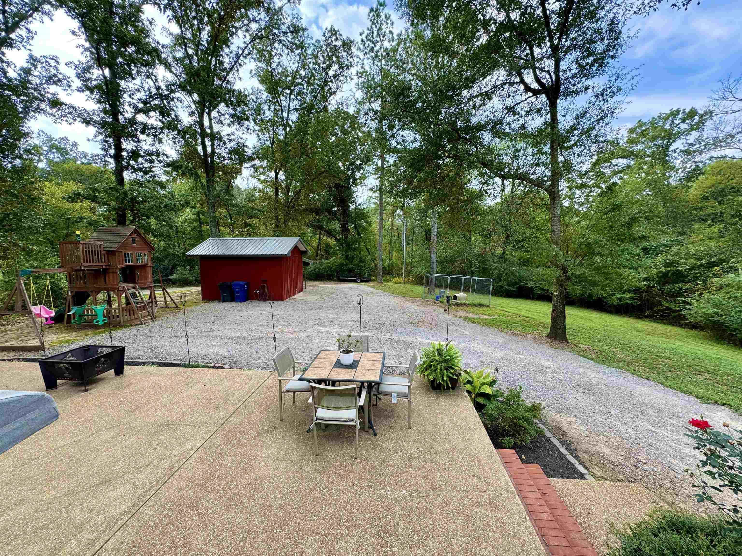 View of patio with a playground and a storage shed