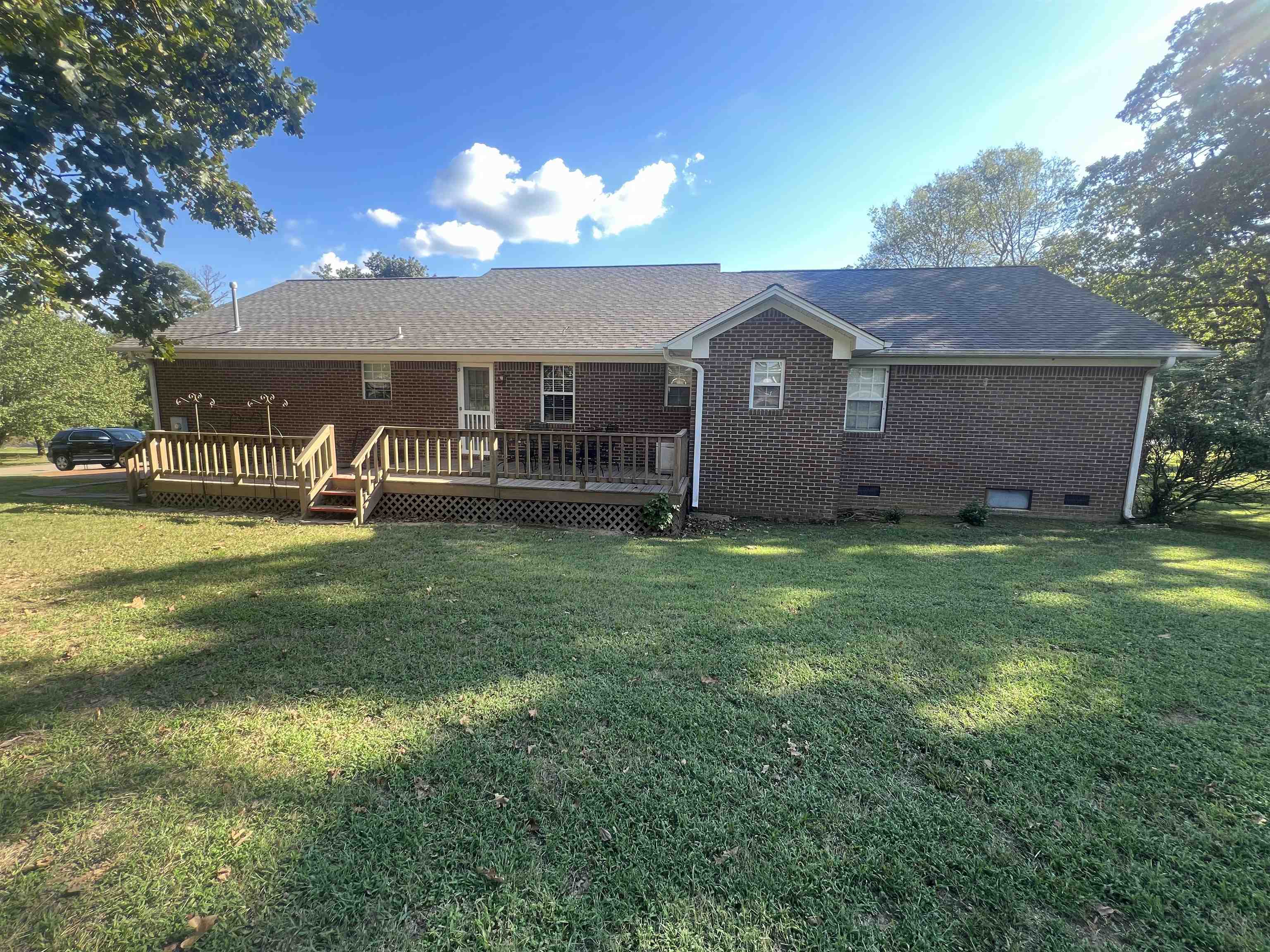 Rear view of property featuring a wooden deck and a lawn