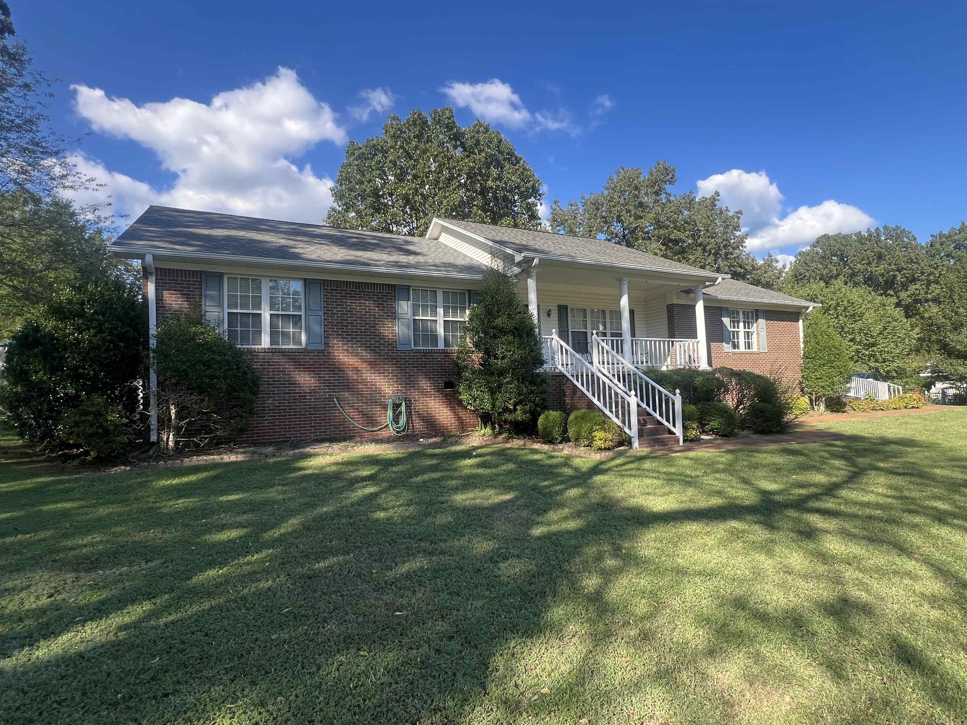 Ranch-style home featuring a front lawn and covered porch