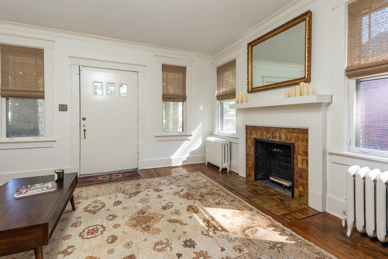 Entryway with radiator, dark wood-type flooring, a fireplace, and crown molding