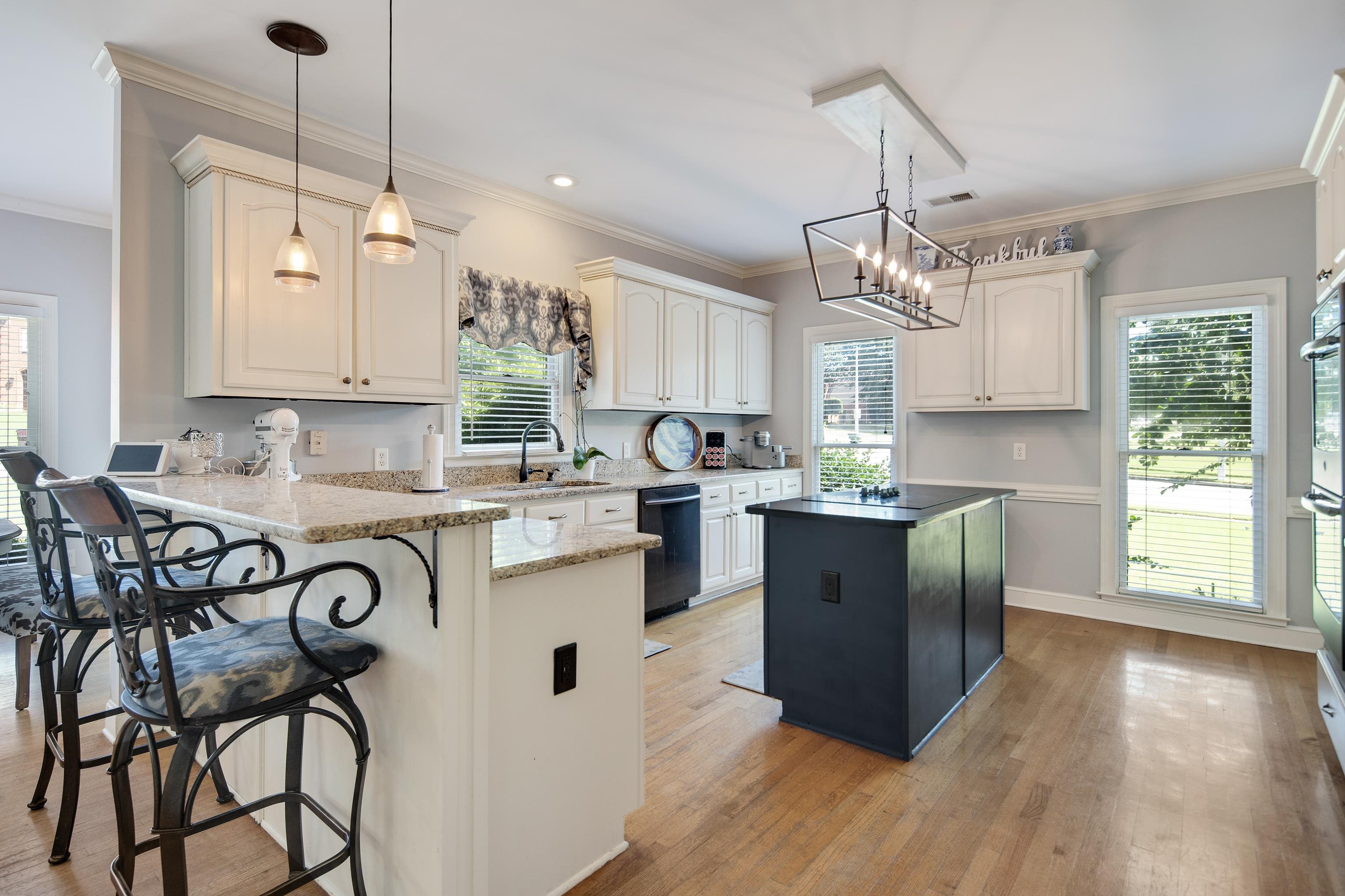 Kitchen with white cabinets, decorative light fixtures, light hardwood / wood-style floors, and kitchen peninsula