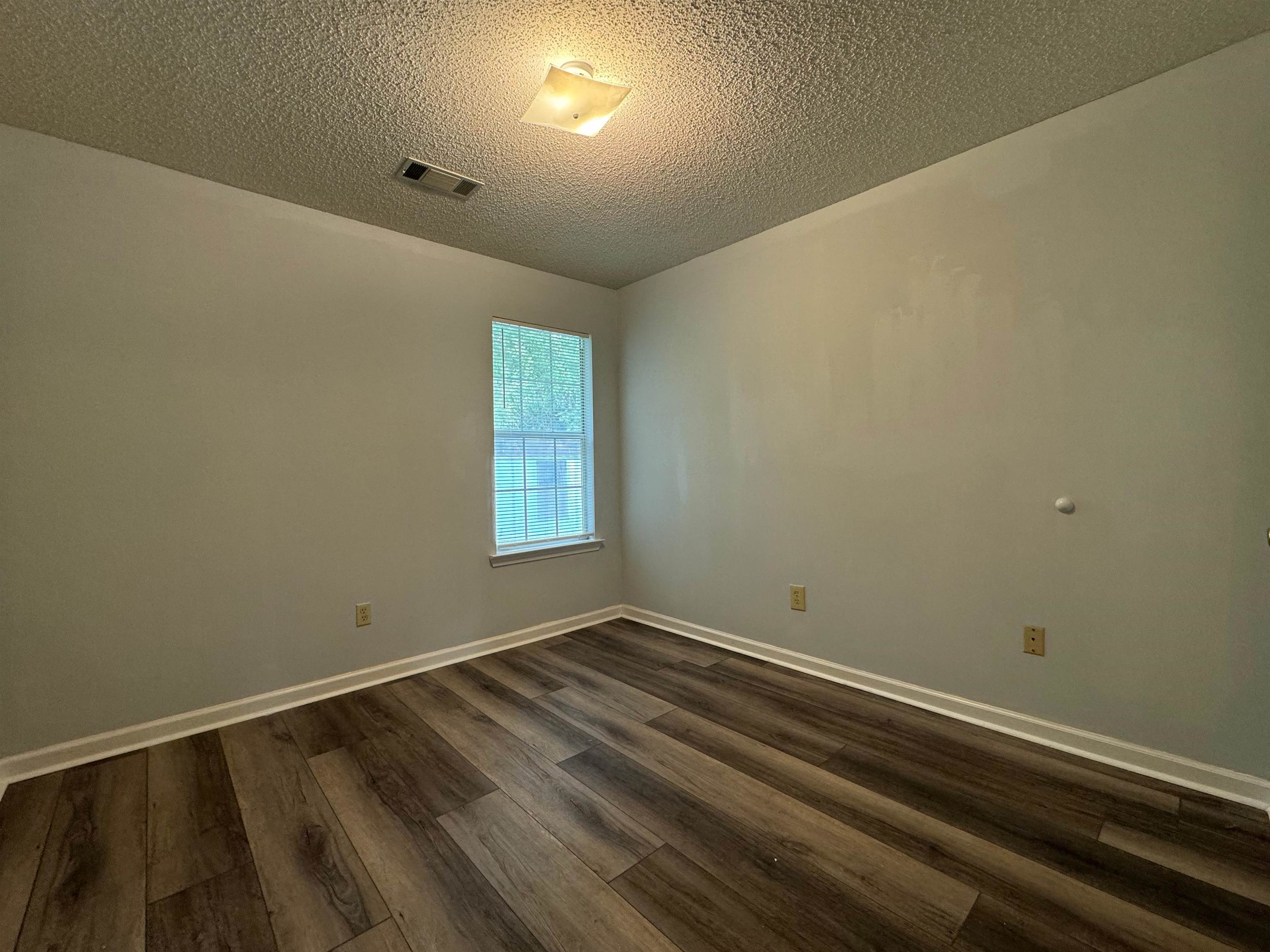 Spare room with a textured ceiling and dark wood-type flooring