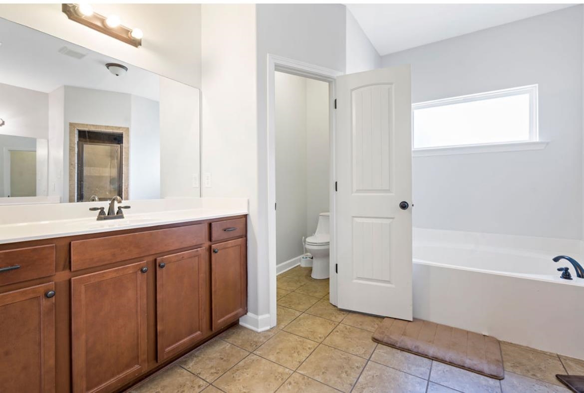 Full bathroom featuring tile patterned floors, separate shower and tub, vanity, and toilet