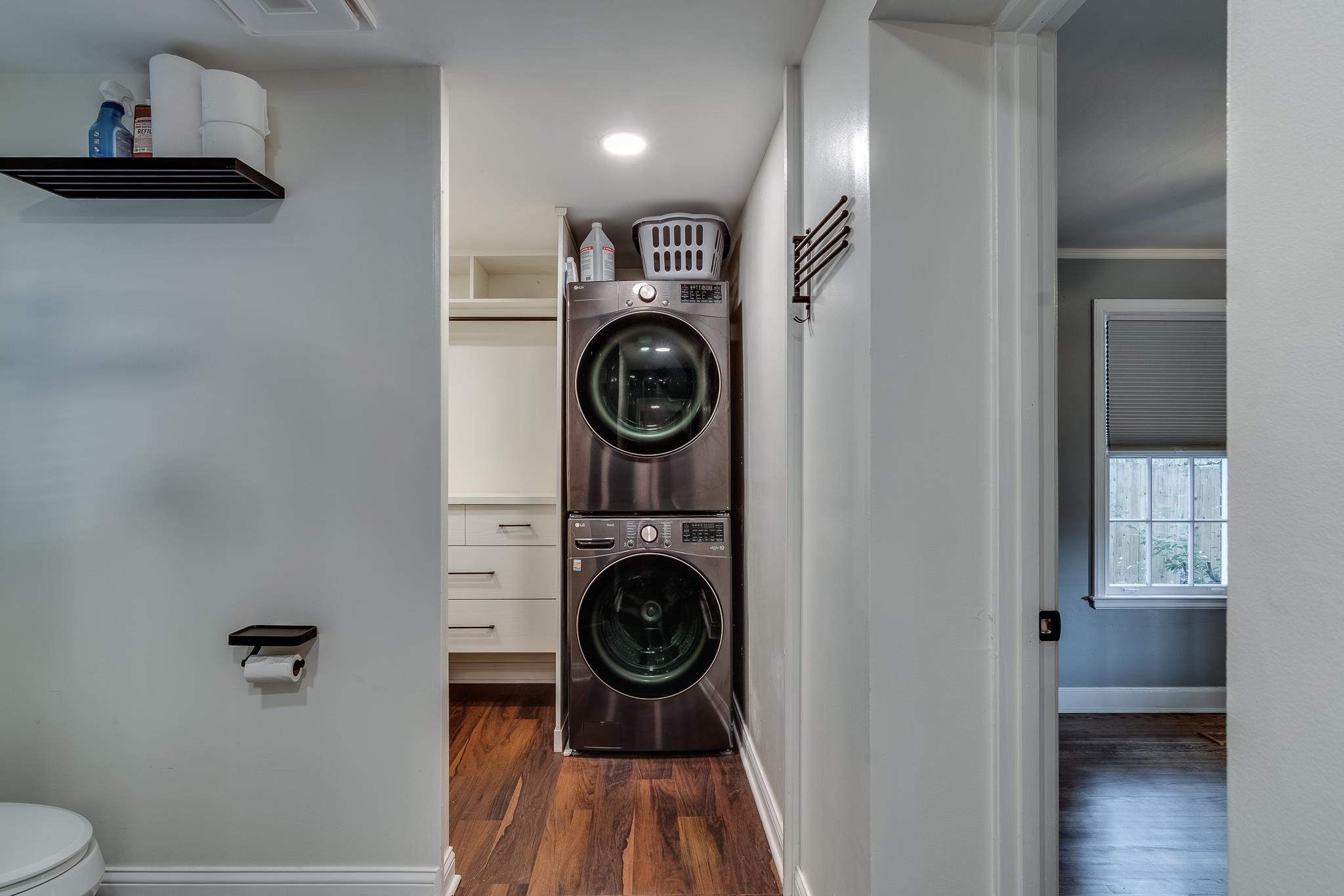 Clothes washing area featuring ornamental molding, stacked washer / dryer, and dark hardwood / wood-style floors