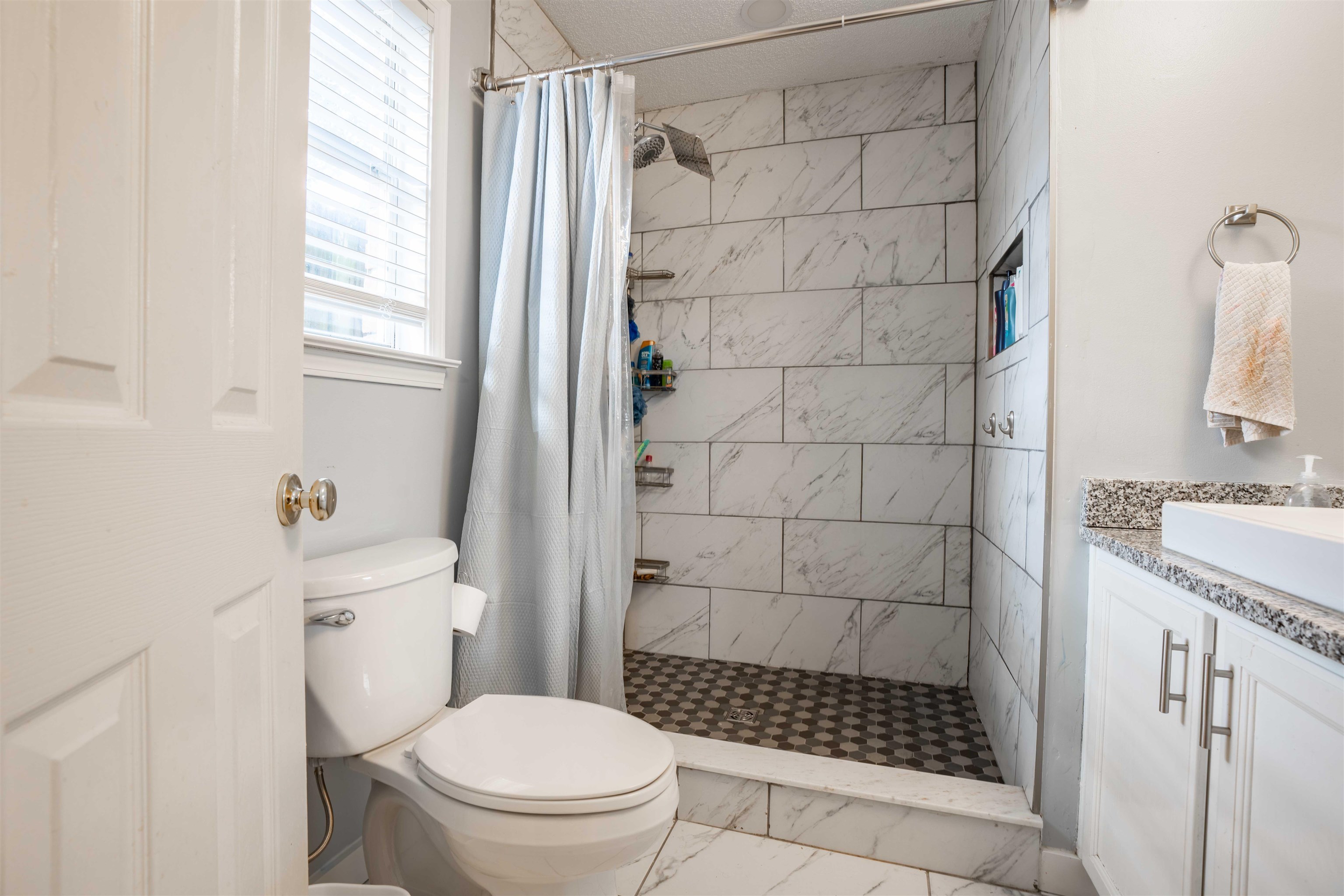 Bathroom featuring a shower with curtain, vanity, and toilet