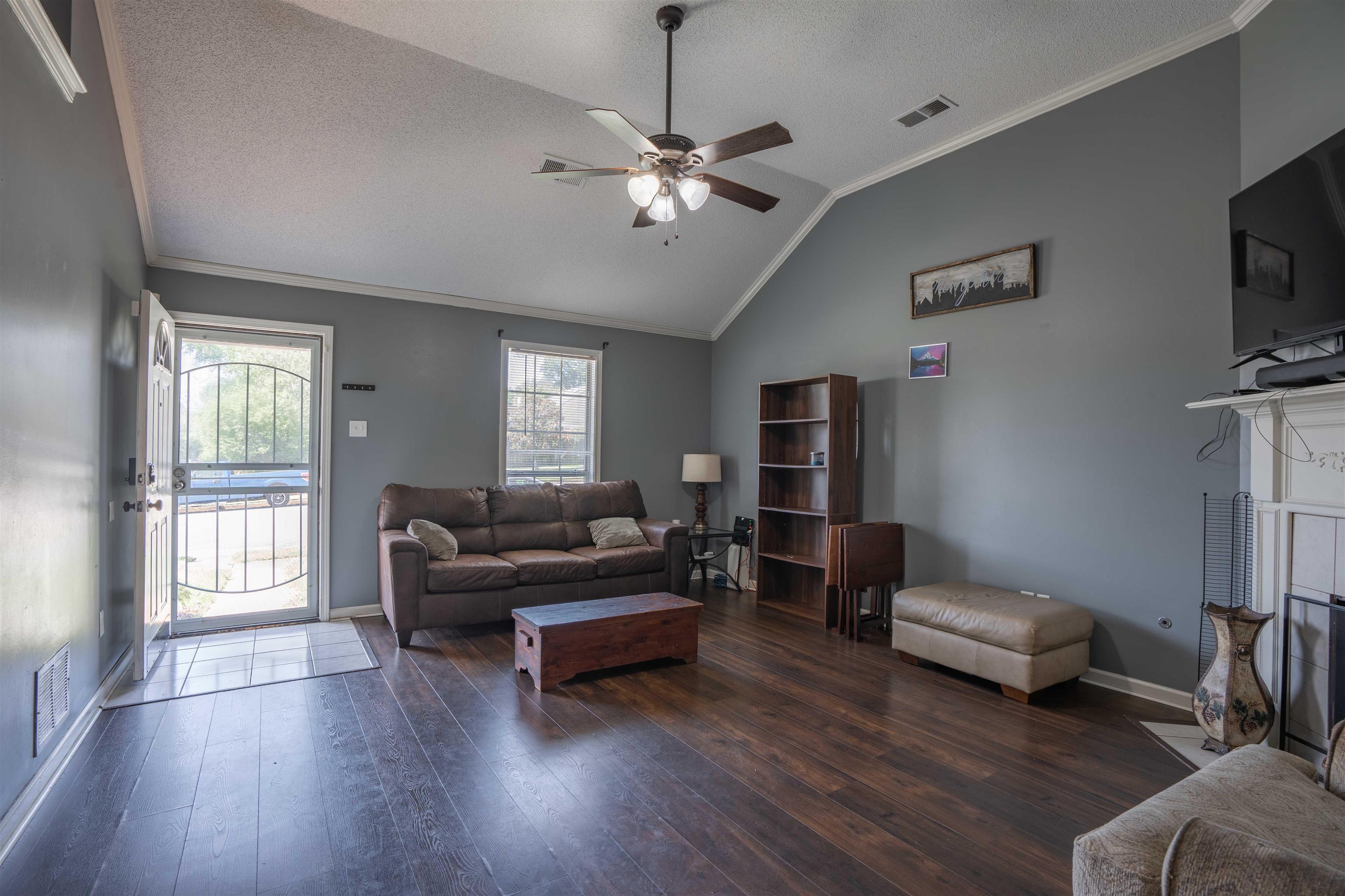 Living room with a healthy amount of sunlight, ceiling fan, and dark wood-type flooring