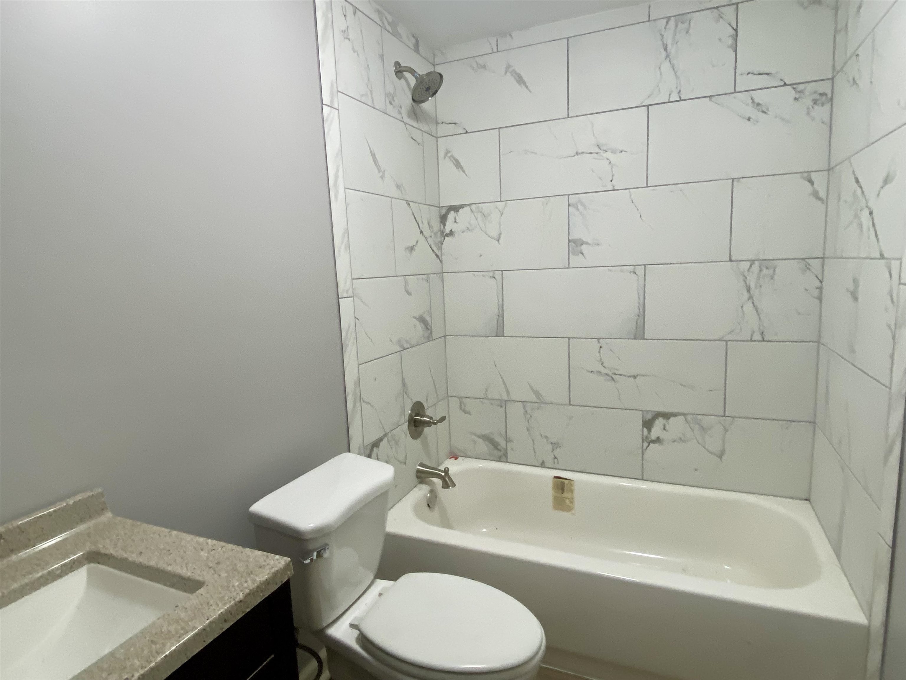 Full bathroom with tiled shower / bath combo, vanity, and toilet