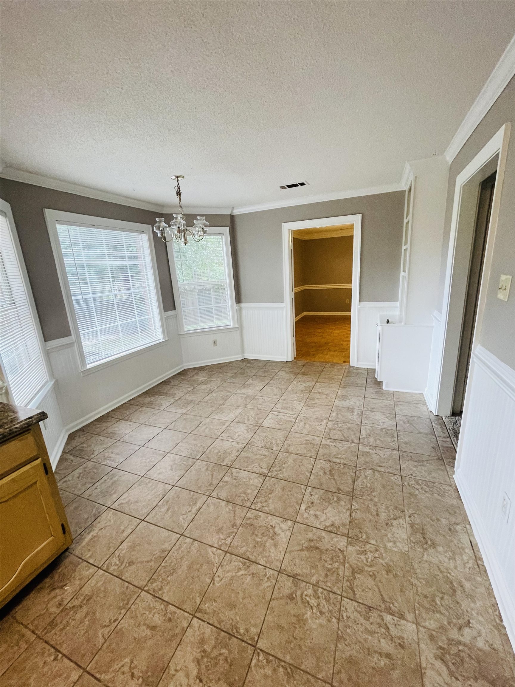 Unfurnished bedroom featuring a chandelier, a closet, a textured ceiling, crown molding, and a spacious closet